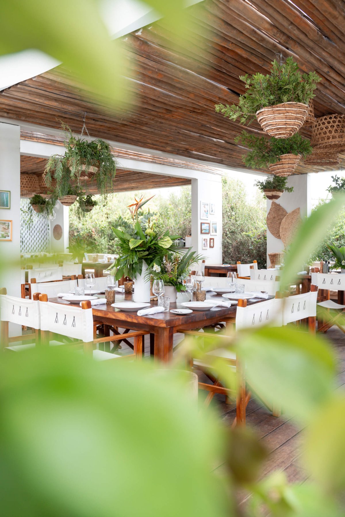 Interior shot of Nikki Beach Costa Smeralda restaurant with leaves in the foreground and the sea in the background
