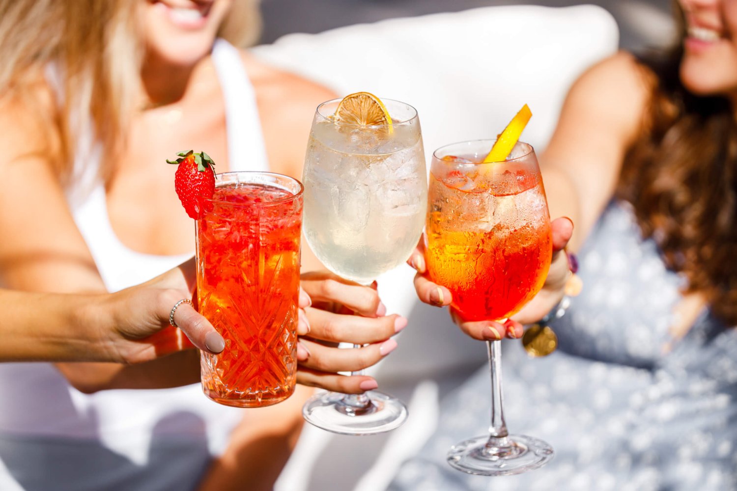 Three women smiling and cheersing glasses of cocktails