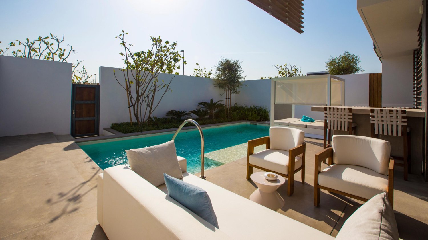 Private pool area with sofas, arm chairs, bar counter and stools