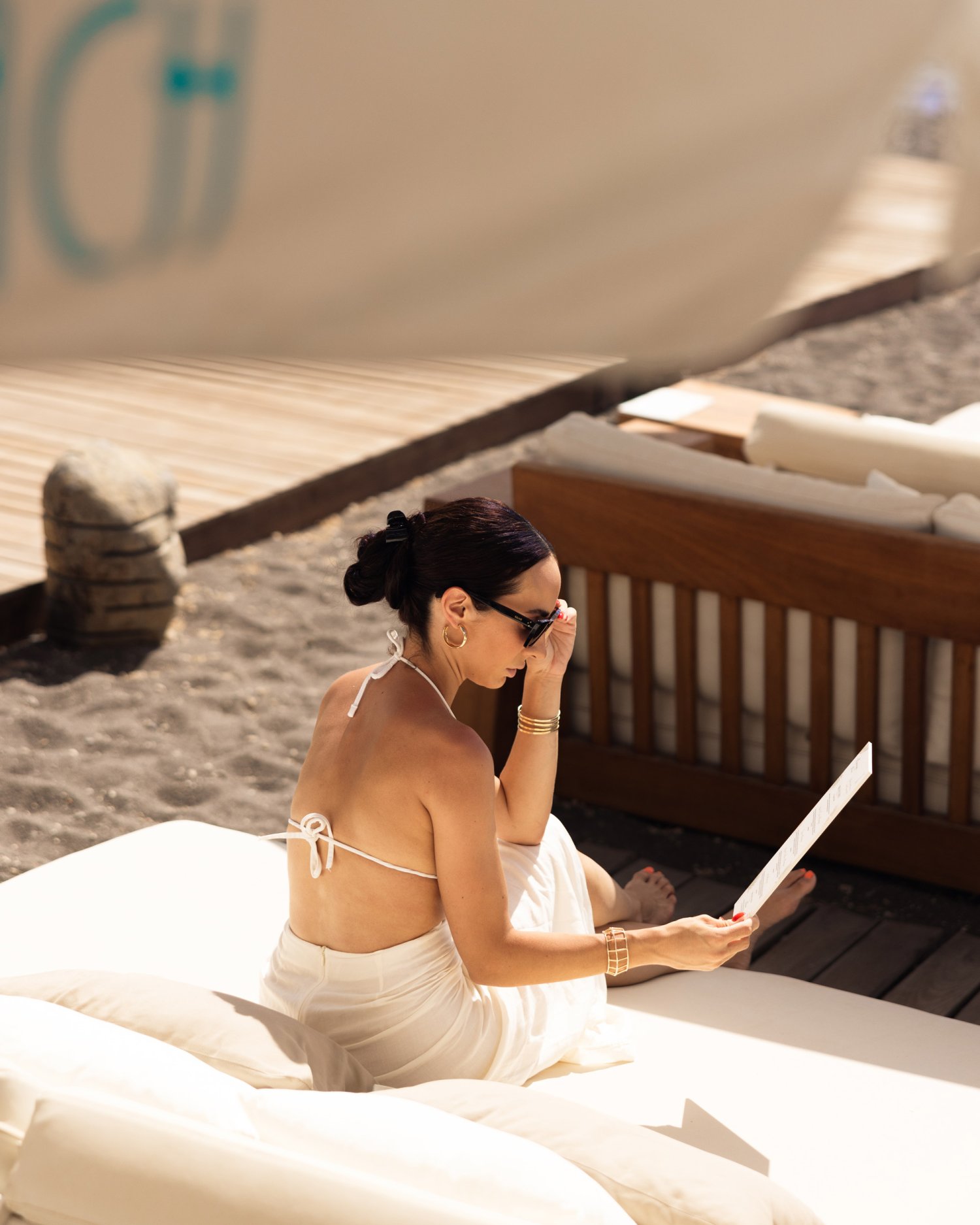 A women sat on a sofa on the beach, reading the Nikki Beach menu