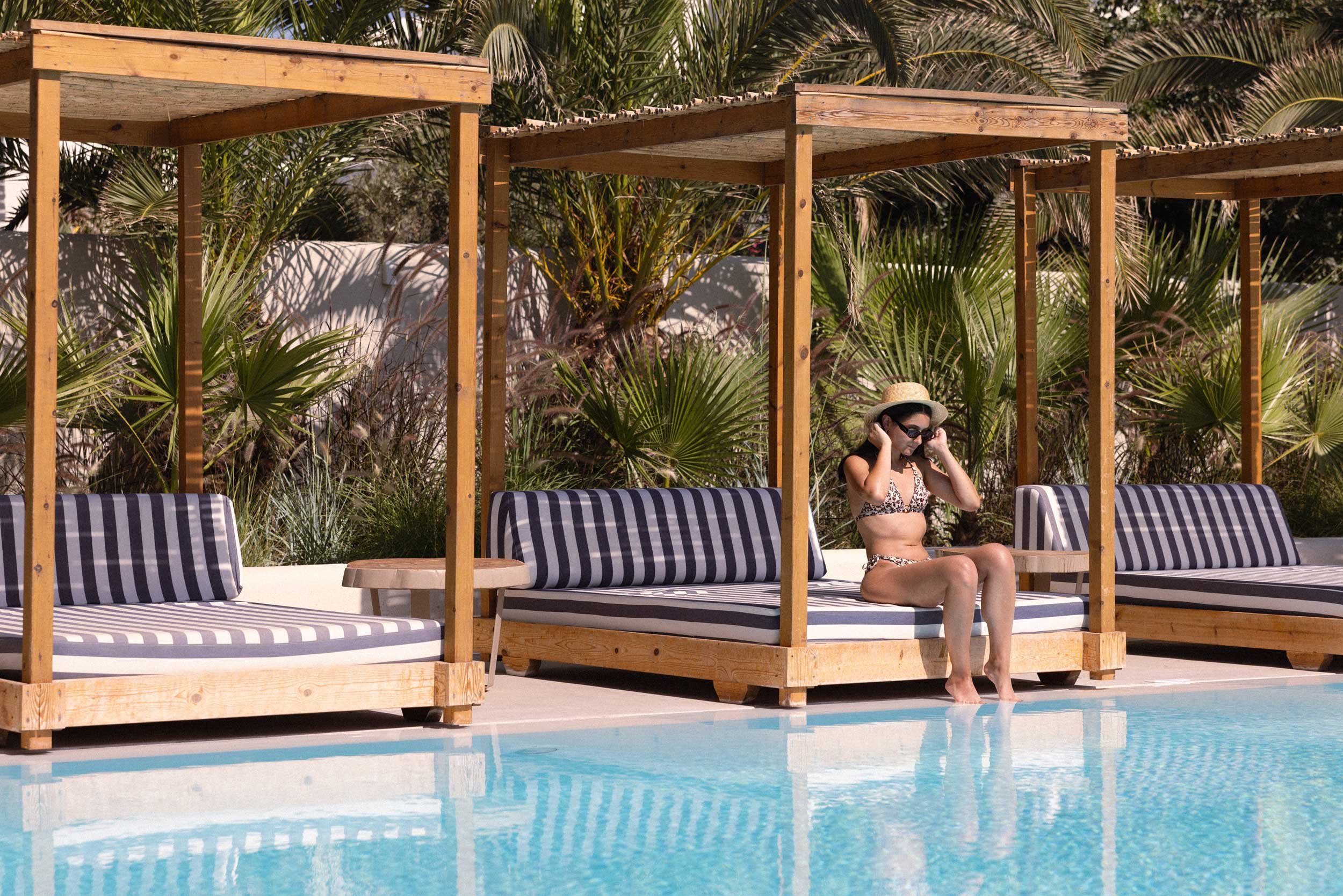 Women sitting under a sheltered sun bed with feet dipped in the pool