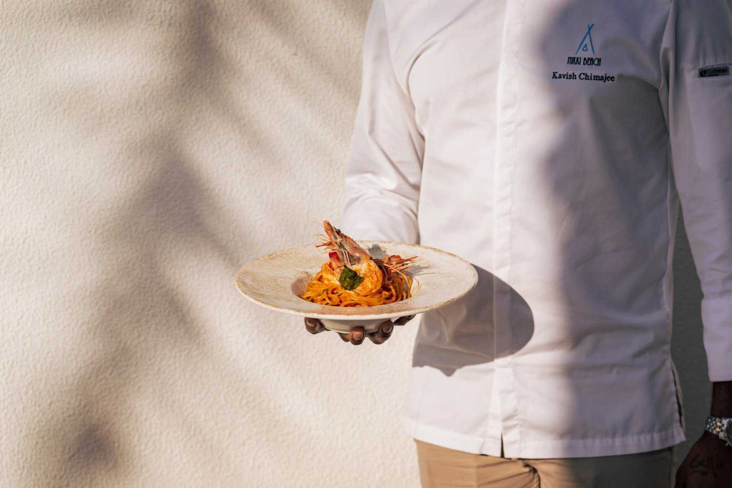 A waiter holding a shrimp pasta dish