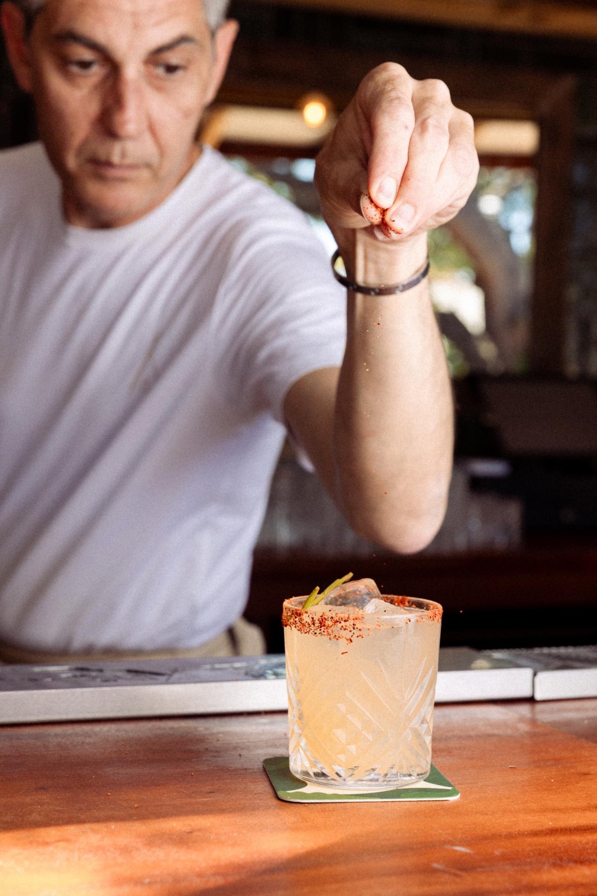 Bartender sprinkling garnish on a cocktail