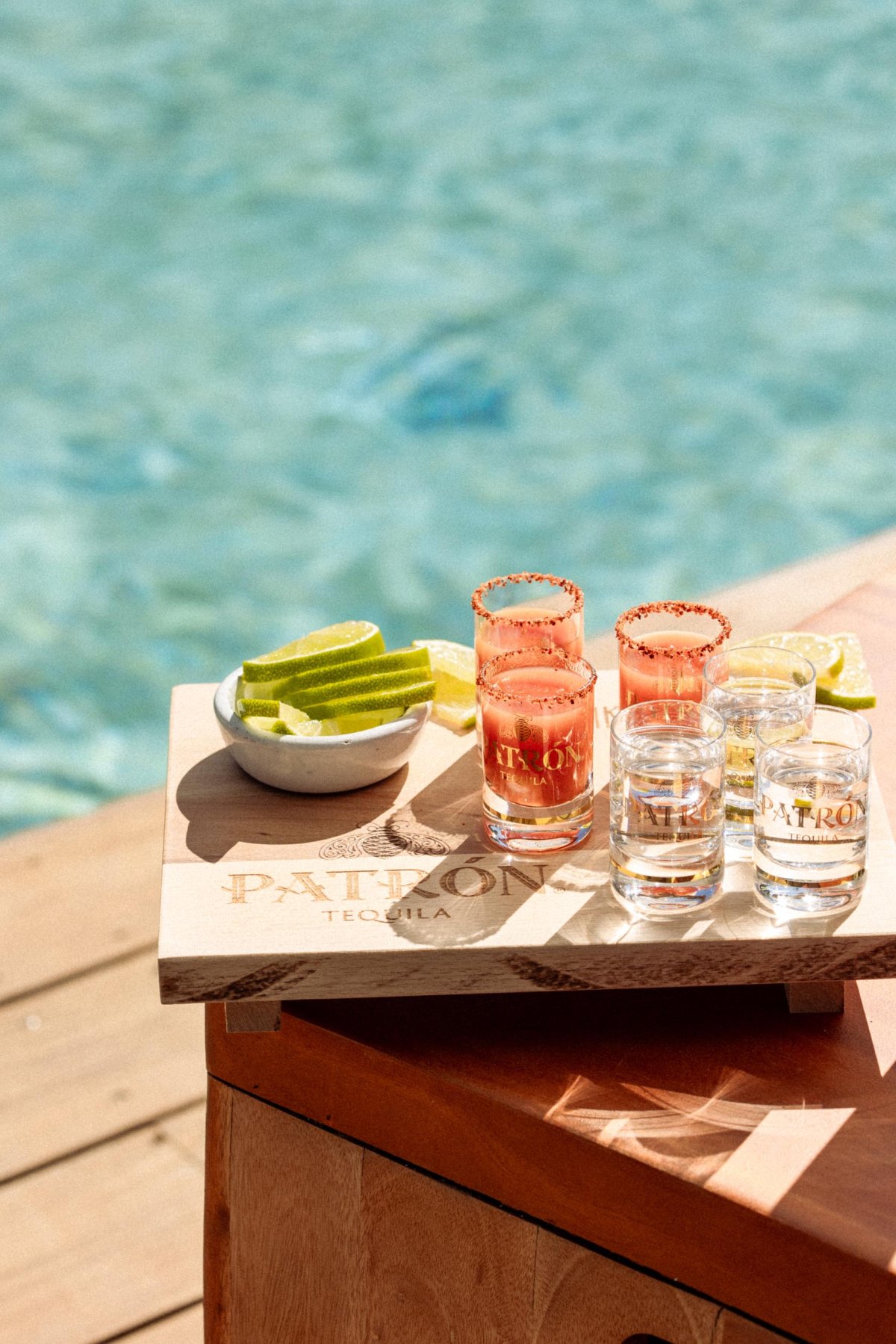 Shot of Patron on a wooden board next to a pool