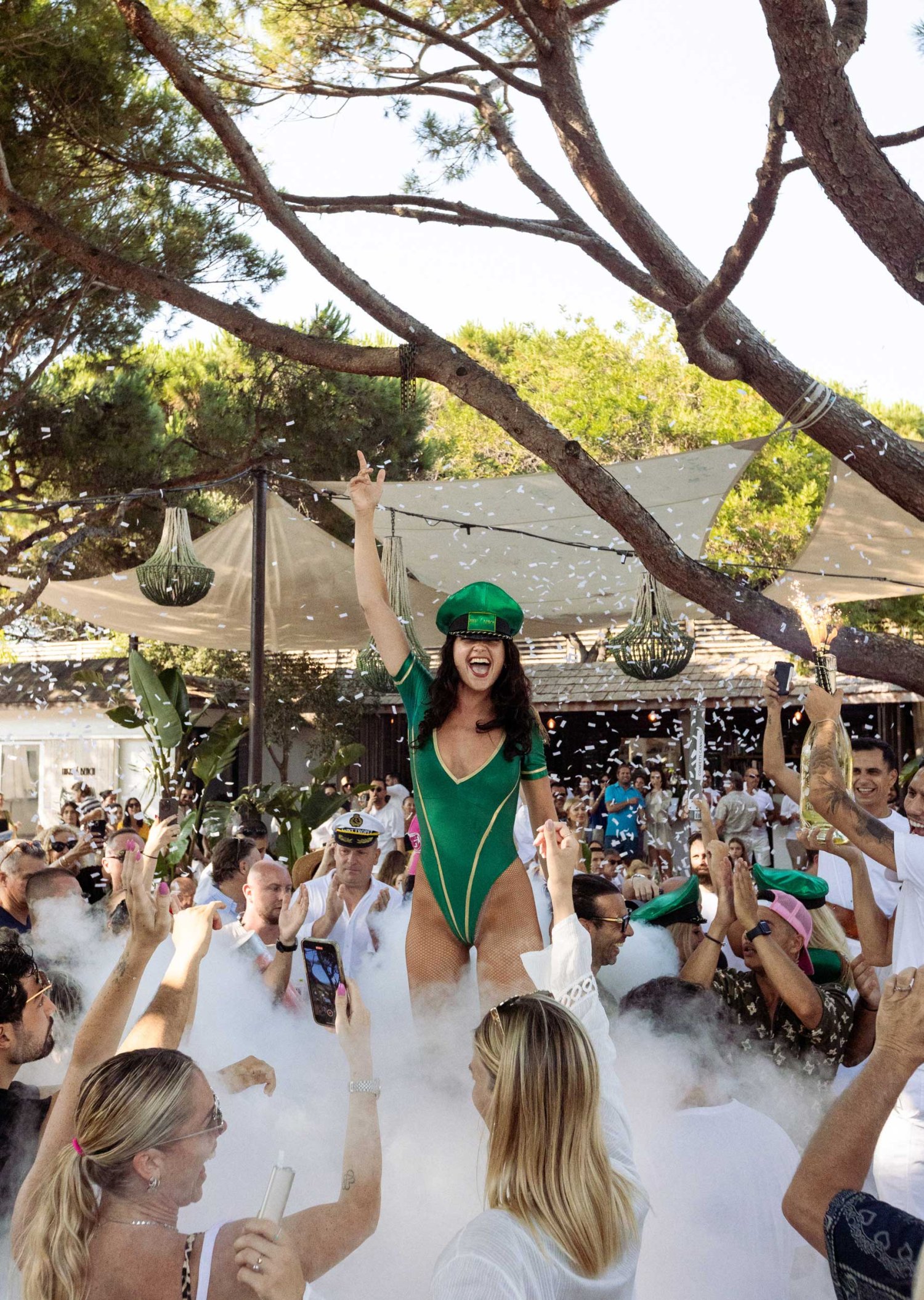 Performer in a green outfit with her hand in the air surrounded by a crowd