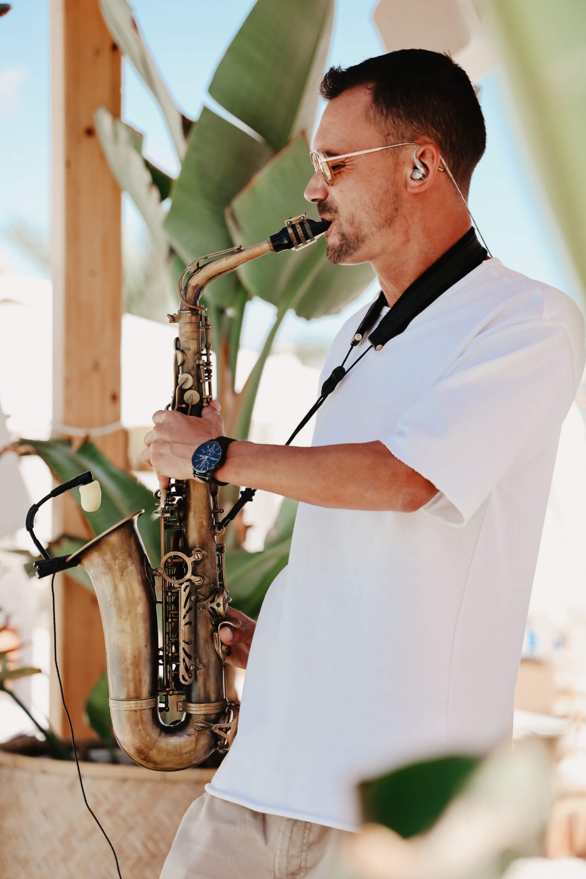 Man wearing a white t-shirt playing the saxophone