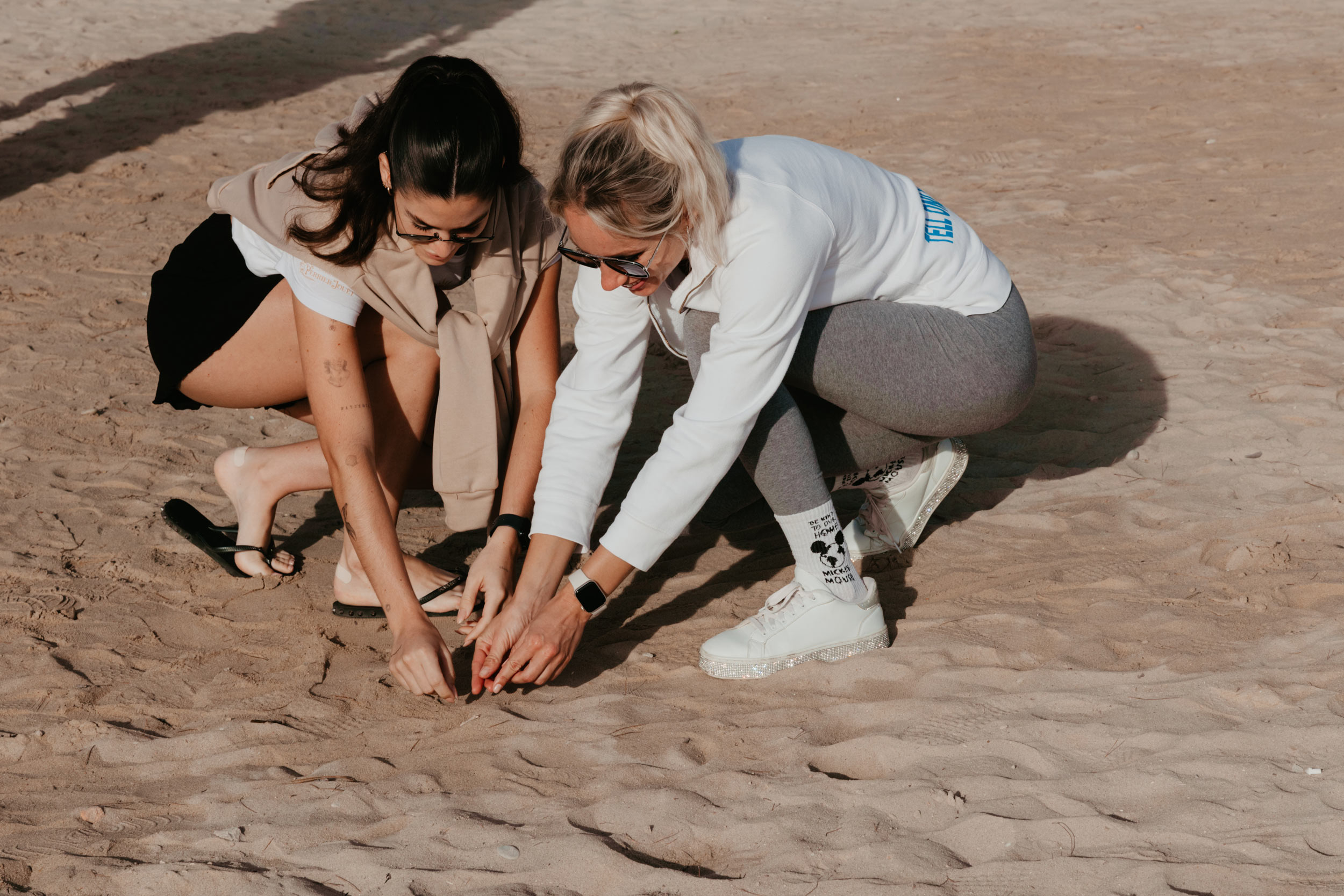 Two women volunteers pulling something out of sand