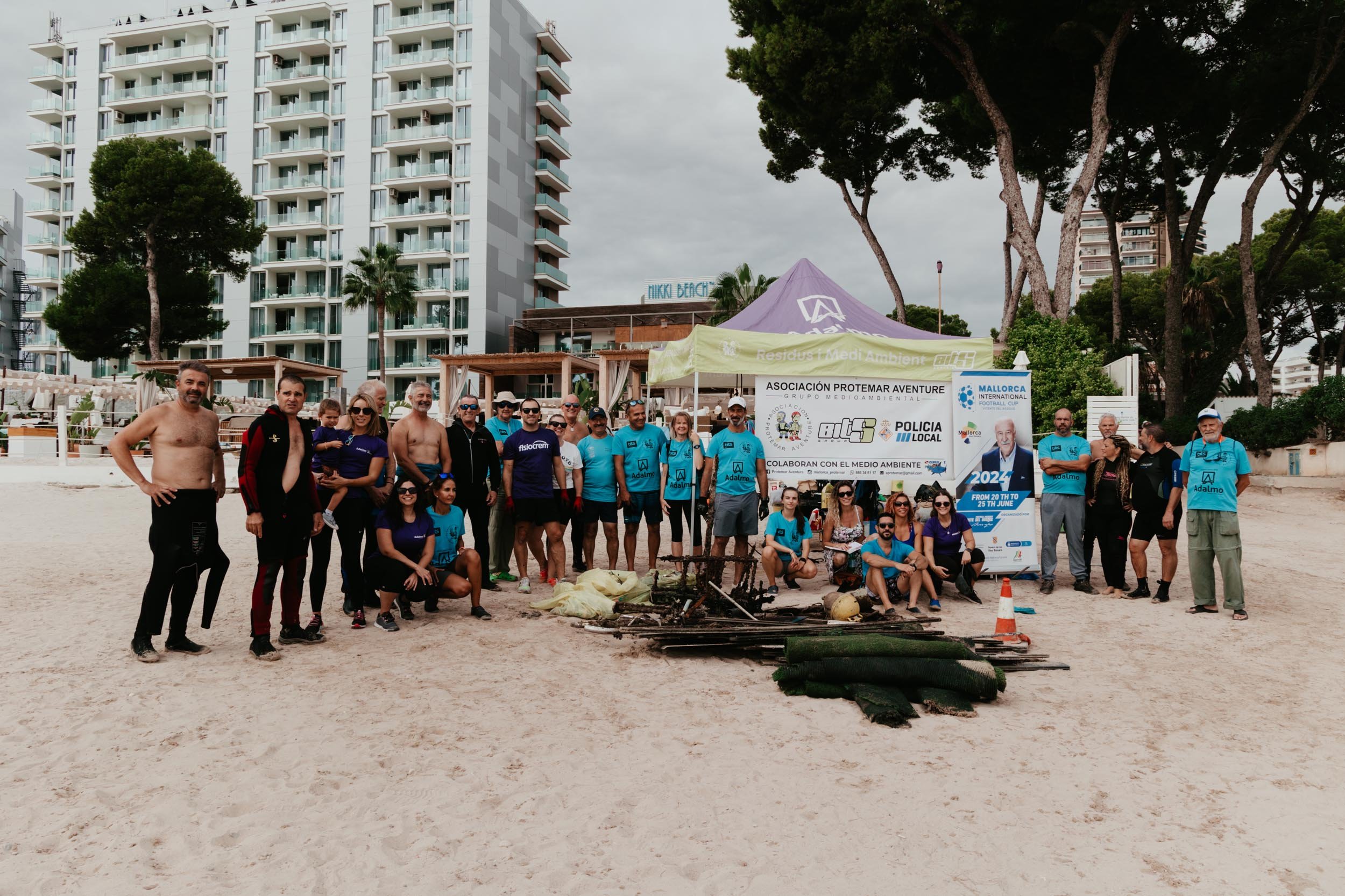 Large group photo of volunteers standing around the pile of litter they had collected from the sea