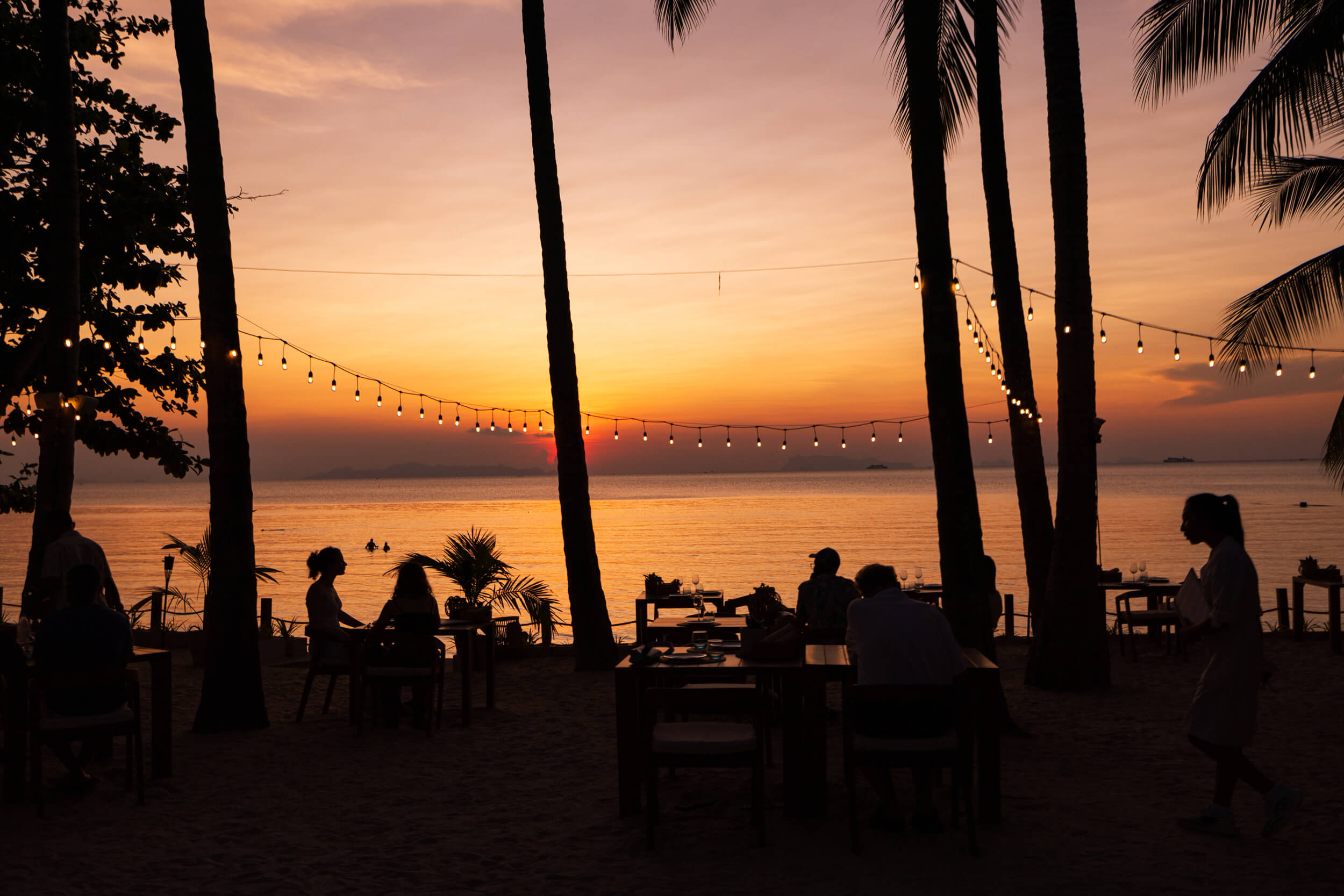 Silhouette of beach restaurant and people walking