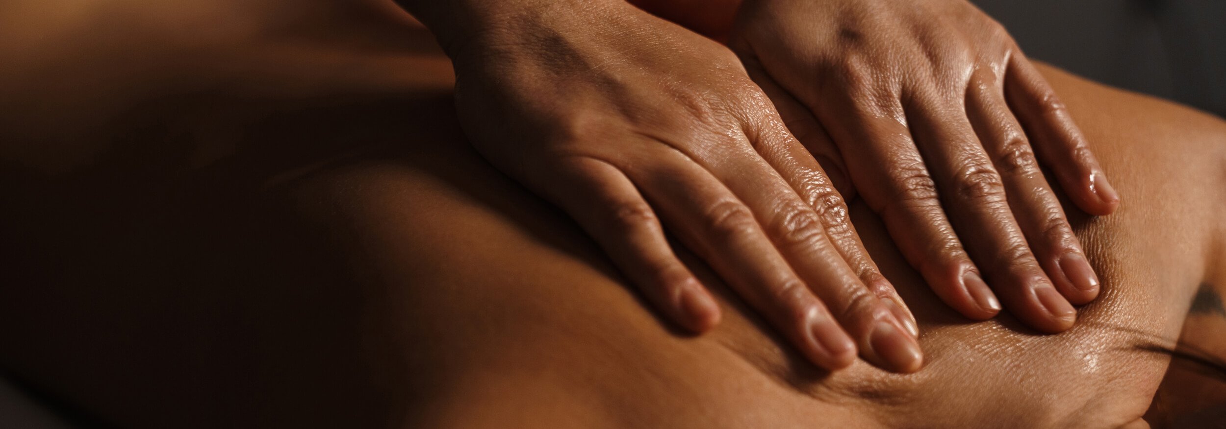 A close up image of of a masseuse massaging someones back