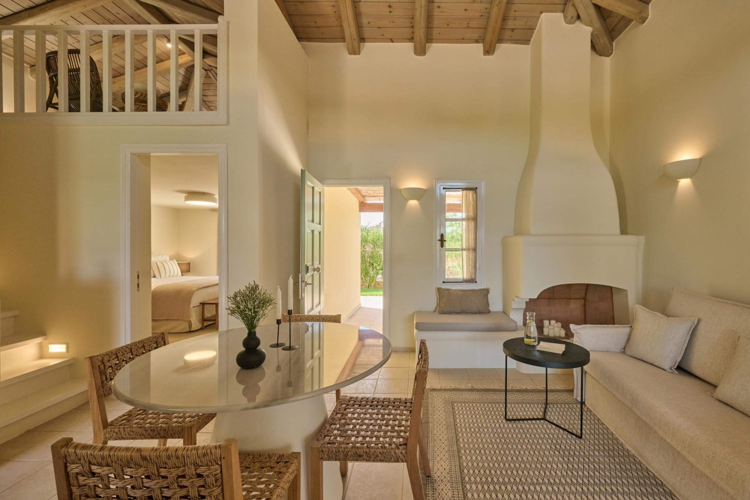 Sofas by fire place. Small round dining table in the centre of the room. A balcony room looking over the living room to the left of the image