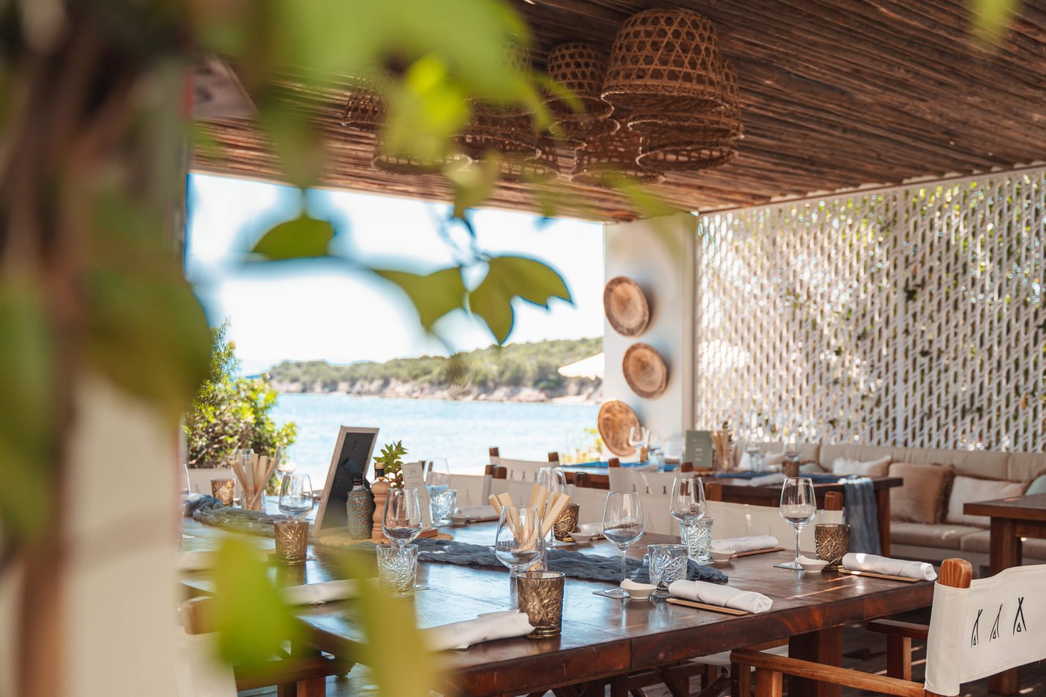 Interior shot of Nikki Beach Costa Smeralda restaurant with leaves in the foreground and the sea in the background