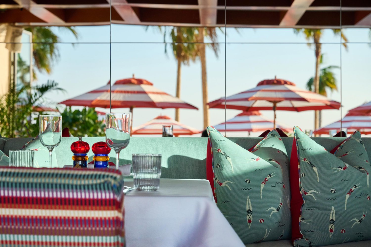 Close up of dining table, seating booth with cushions and glasses laid on table