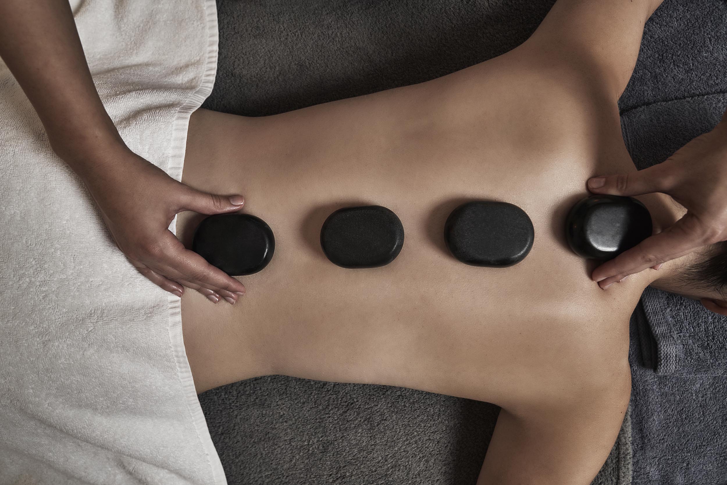 A person in a spa with stones laid over their back
