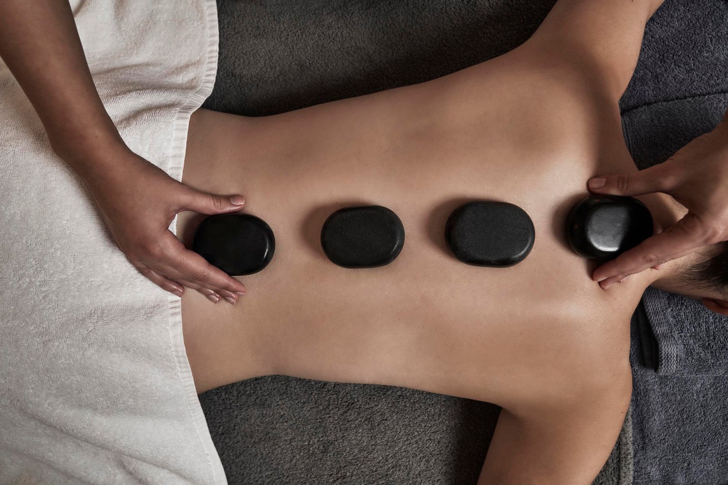 A person in a spa with stones laid over their back