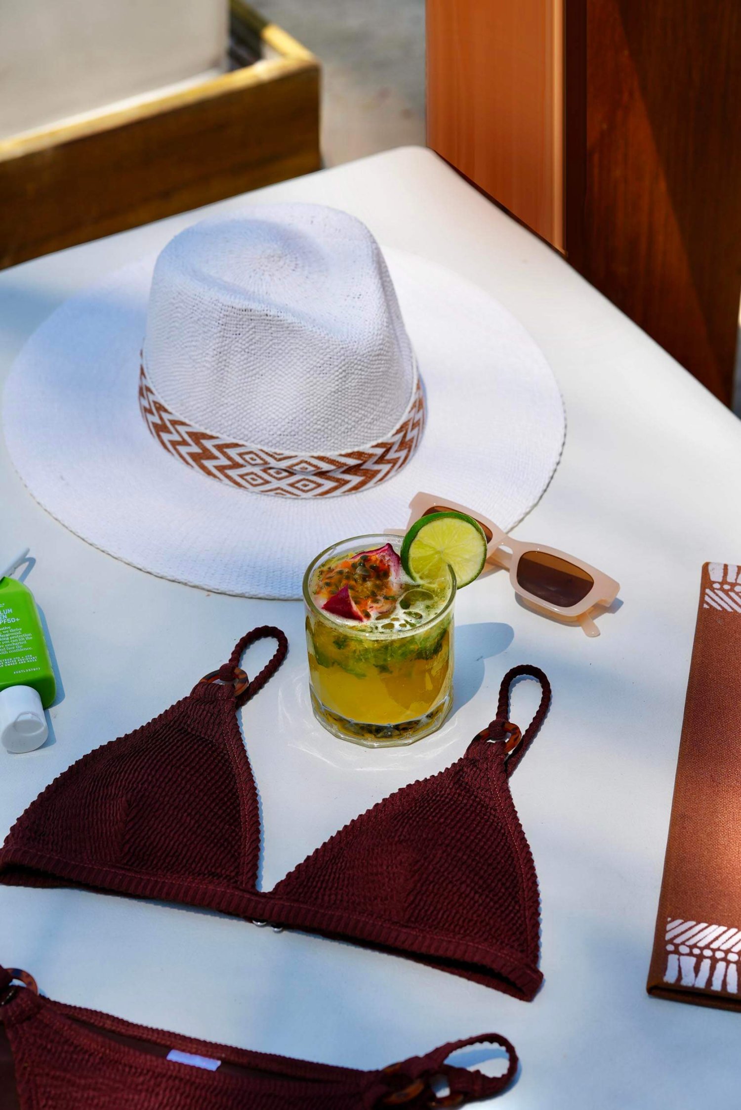 A tropical cocktail on a sun lounger with a sun hat, sun glasses and a bikini neatly laid around the drink