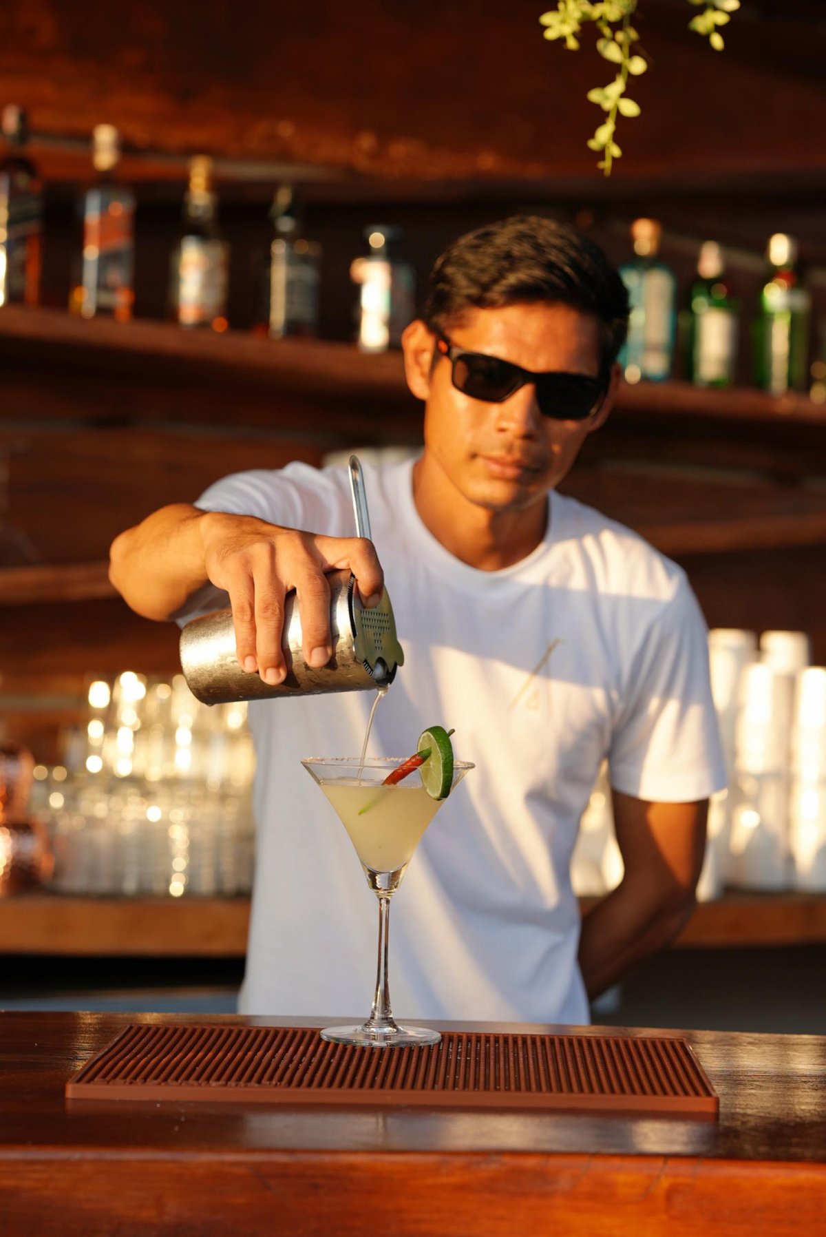A bartender pouring a cocktail from a shaker