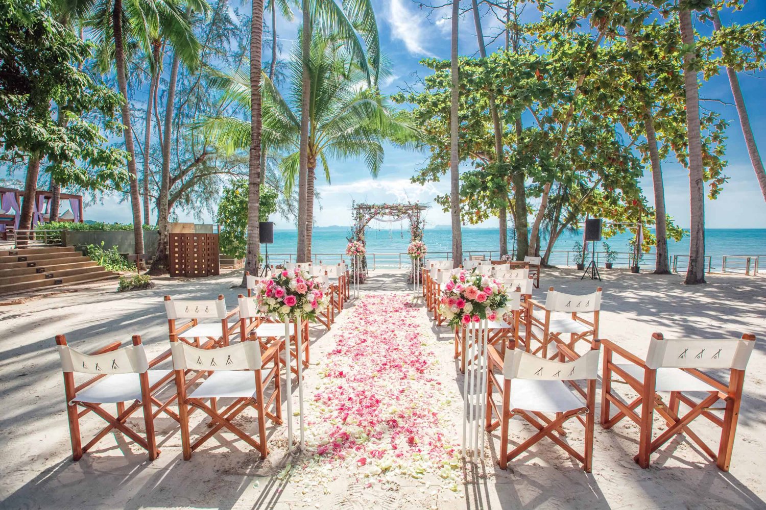 Shot of wedding aisle along the beach with rose petals and chairs either side