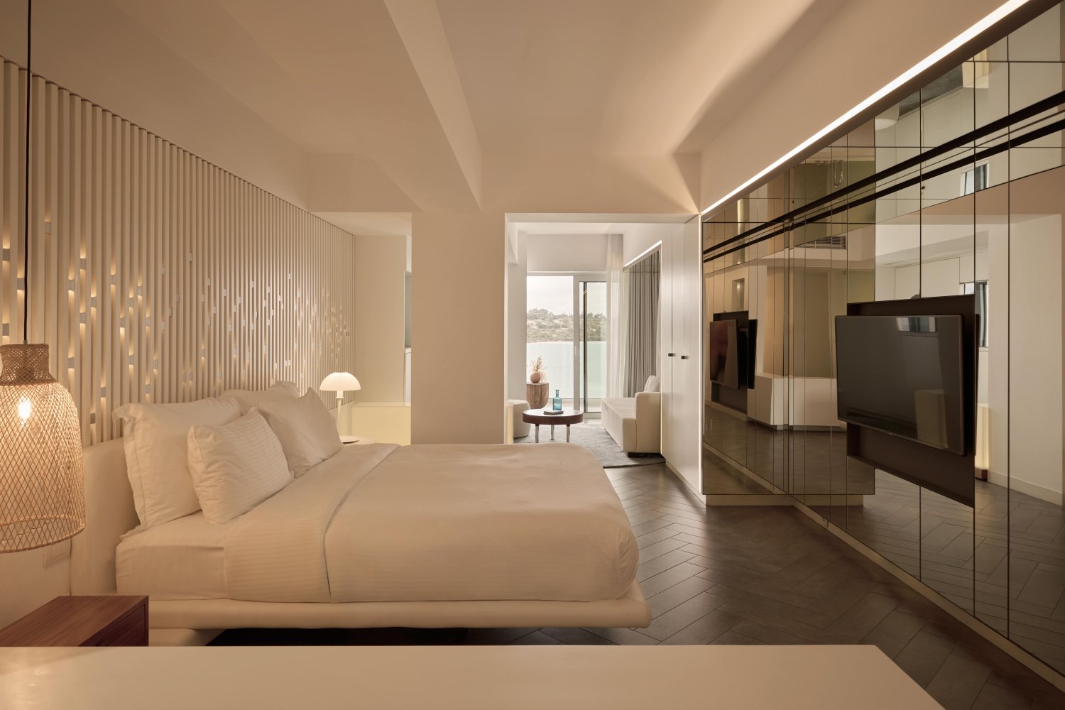 A luxurious room featuring a plush bed, a sleek television, and an elegant mirror reflecting the sophisticated decor