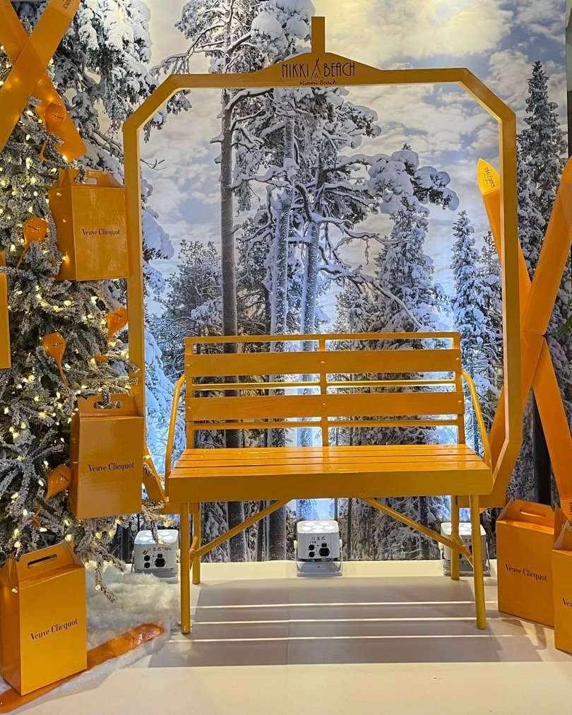Yellow seating area surrounded by snowy trees and a christmas tree