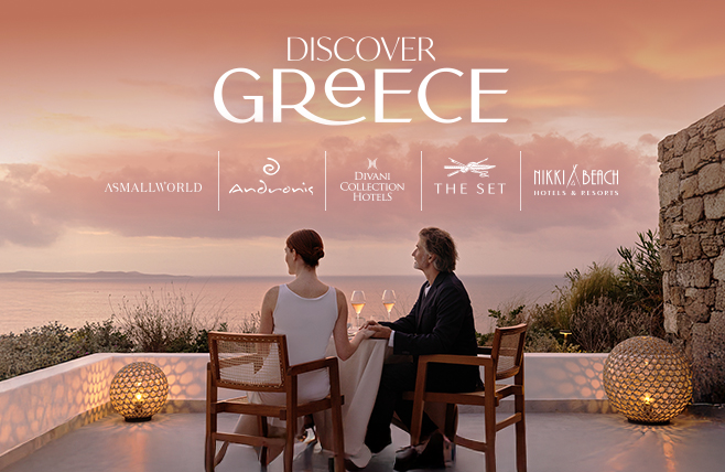 A couple sits together at an elegant outdoor dining table on a terrace overlooking a calm sea at sunset, illuminated by glowing, spherical floor lamps. The graphic includes the prominent text 