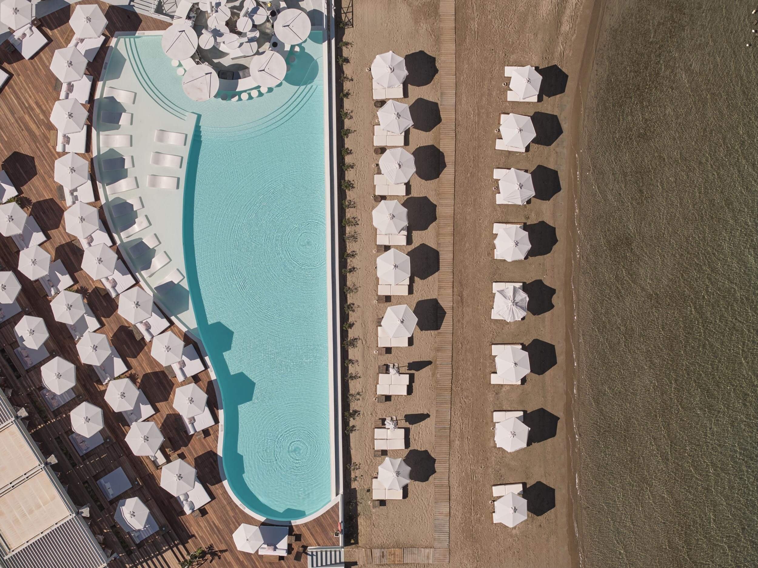 Ariel shot of sun beds around the pool as well as on the beach next to the sea