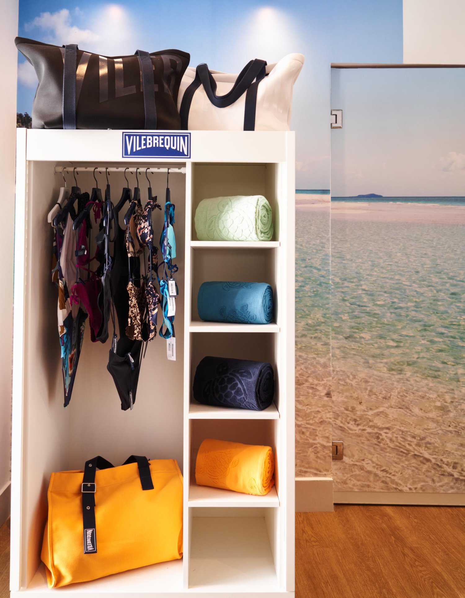 A Vilebrequin display with swimsuits hanging up and folded towels on shelves