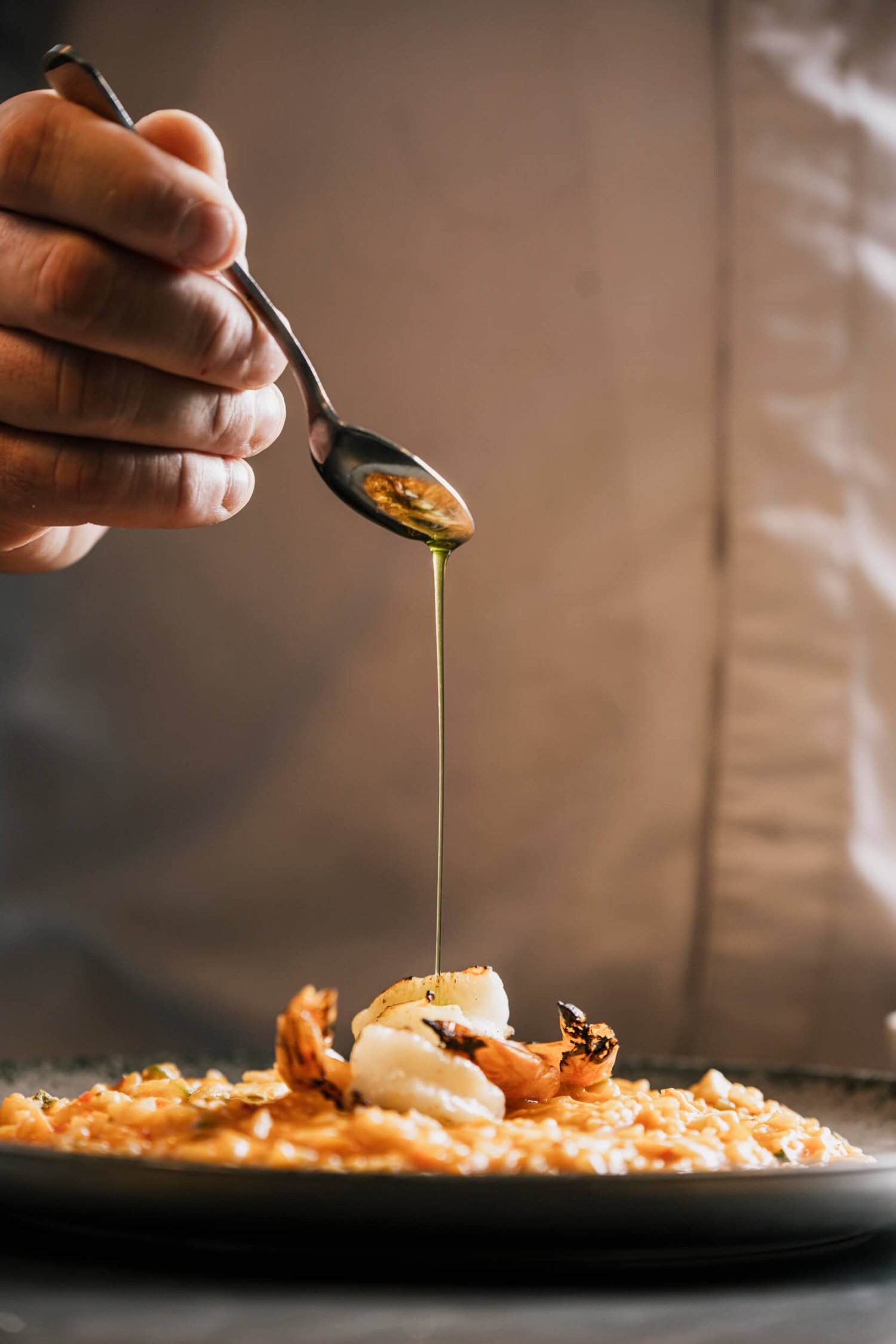 Oil being dribbled onto prawn risotto