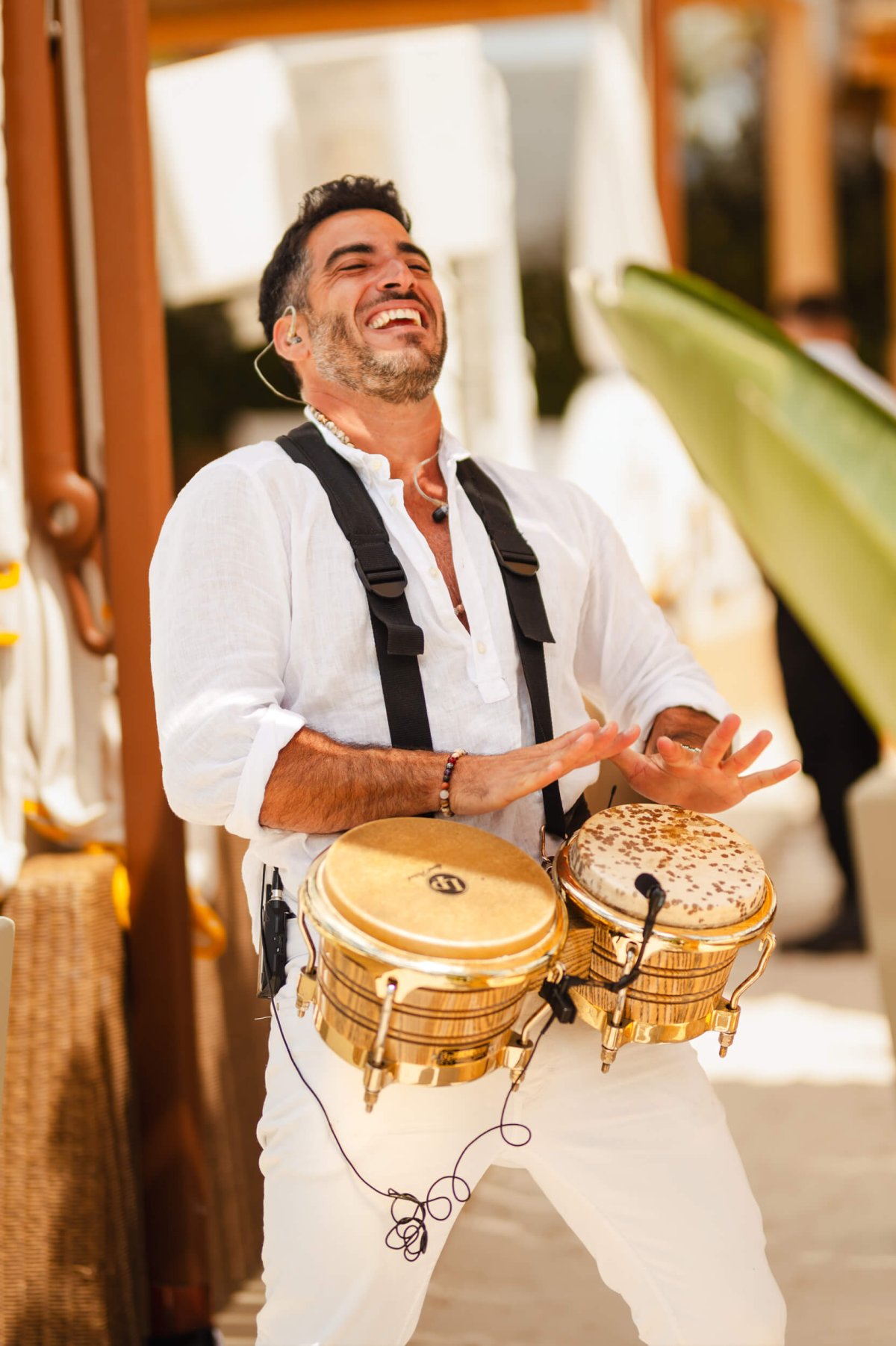 Smiling man in a white shirt beating two drums
