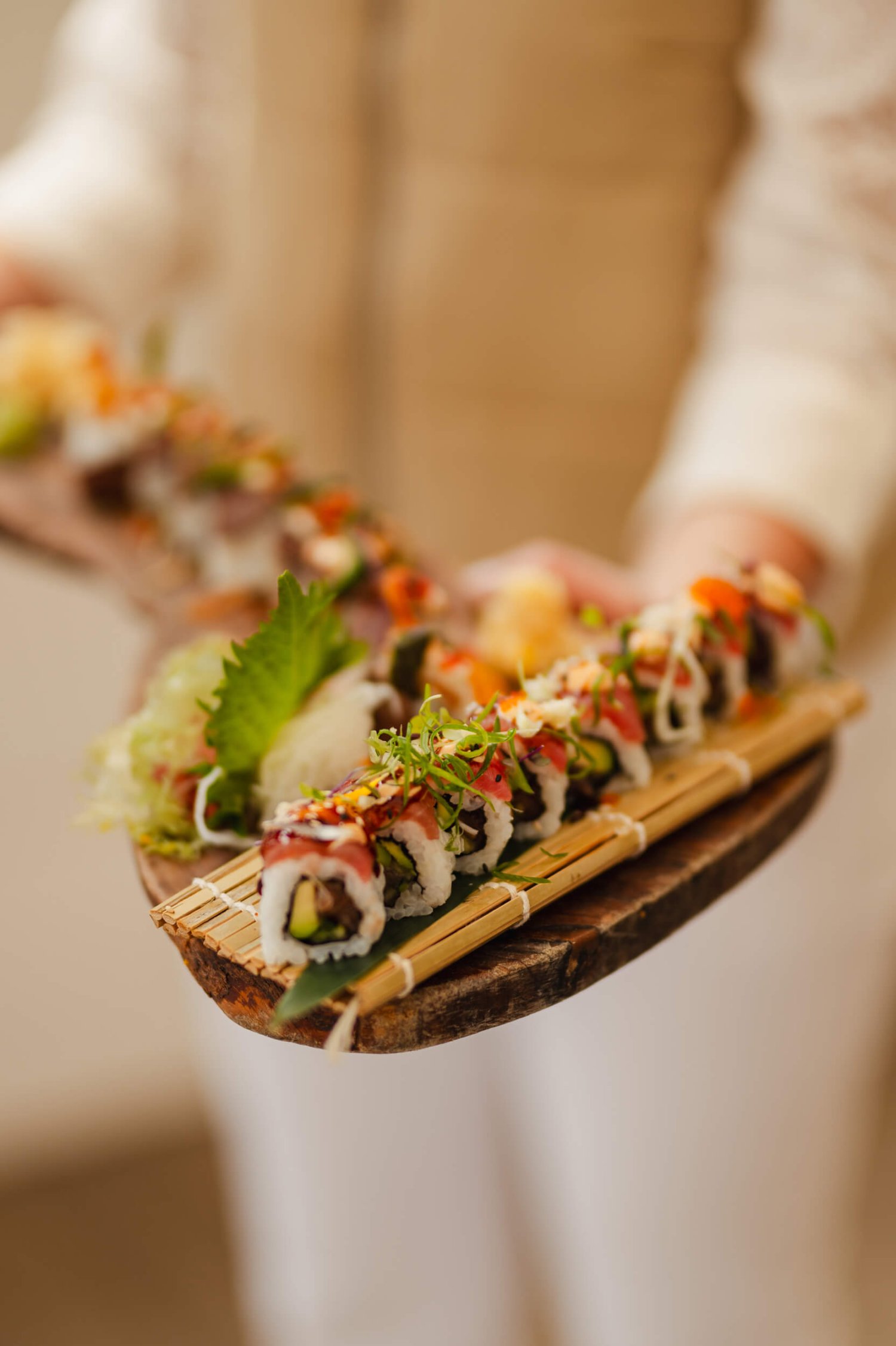 Sushi platter on a wooden board held by a waiter