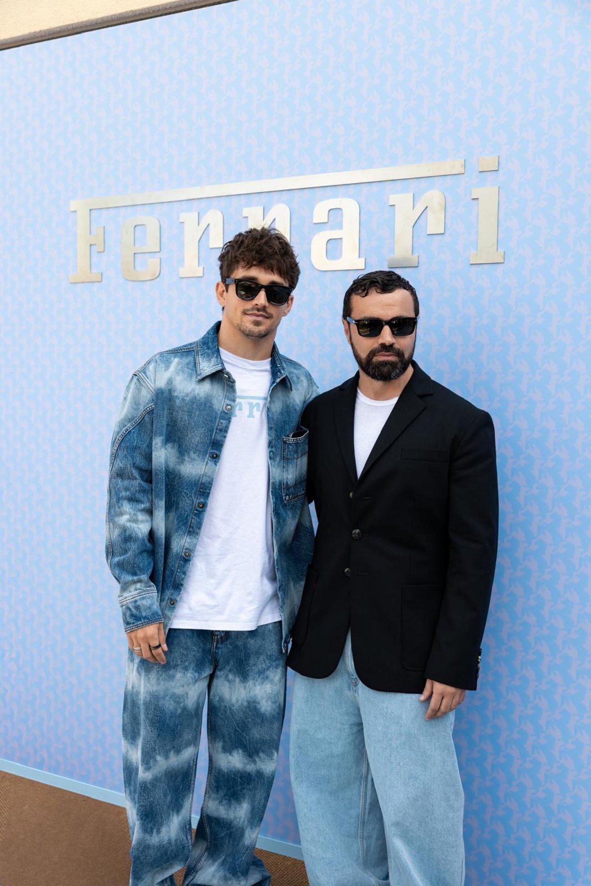 Special guests posing for a photo in front of the Ferrari logo