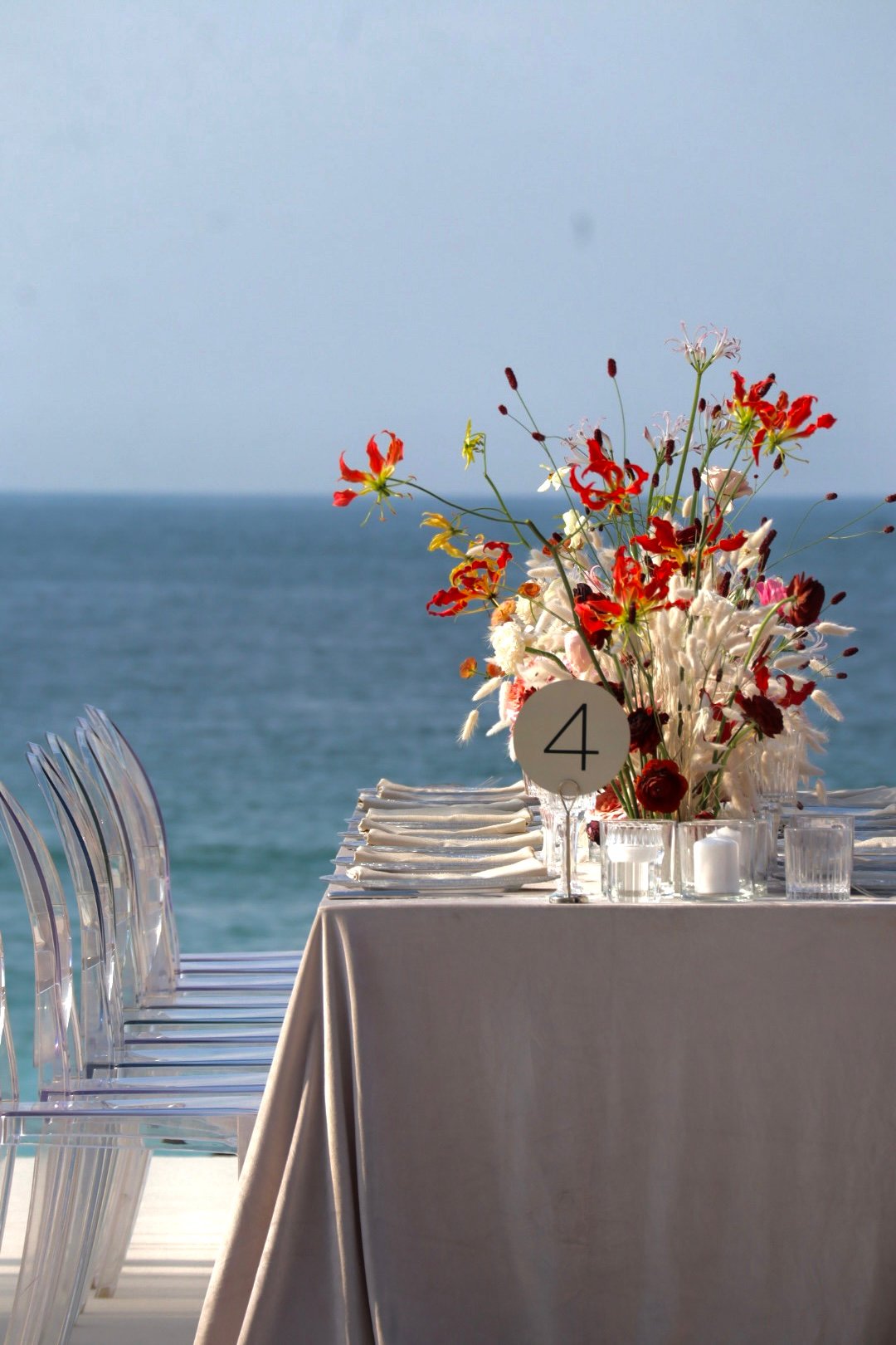 Floral decoration and table number displayed on top of a dining table, sea view behind the table