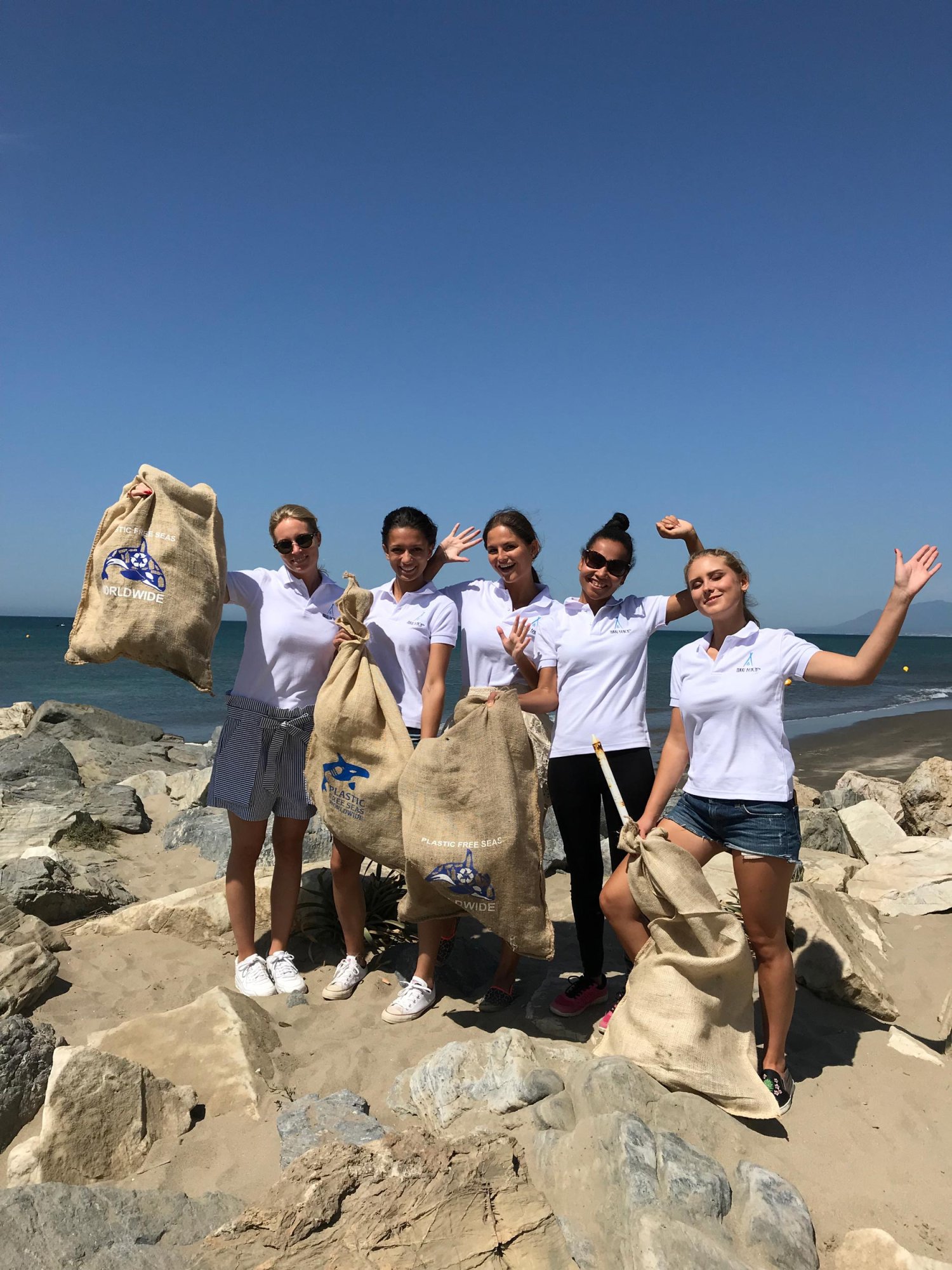 A group of young female volunteers holding rubble sacks on the beach