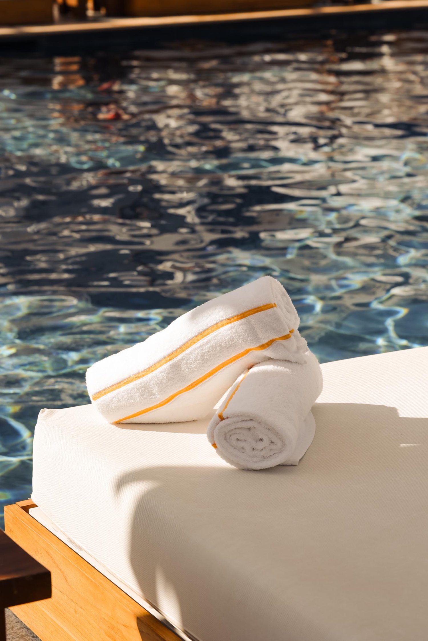 Towels on the edge of a sun lounger next to the pool
