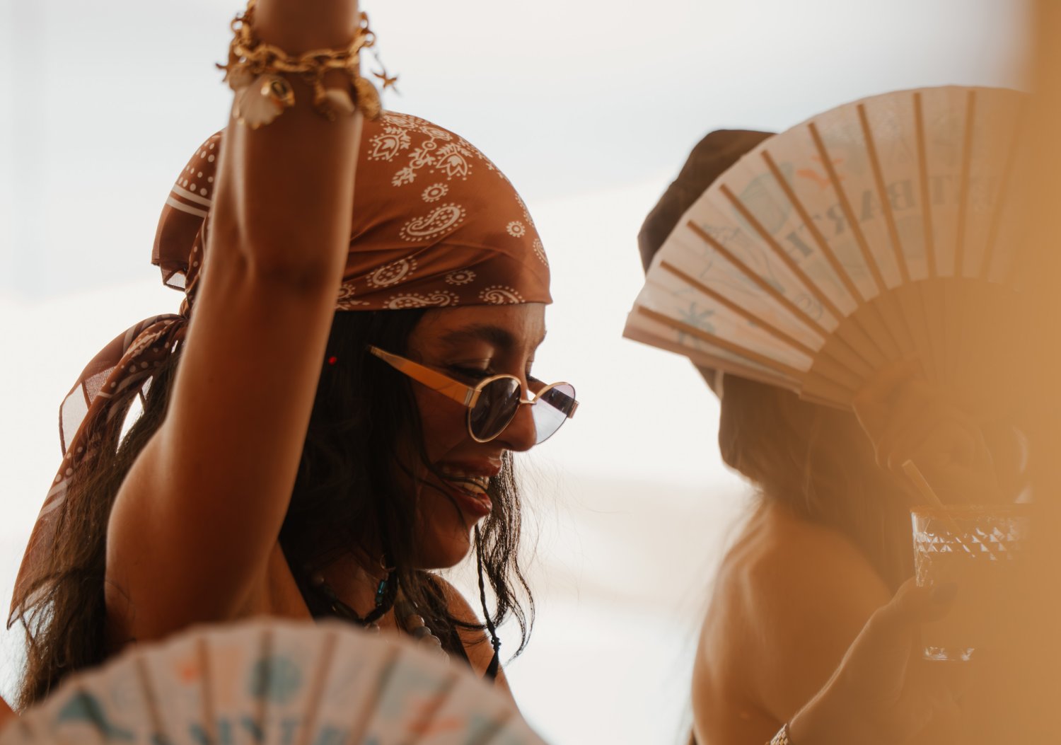 Women wearing a bandanna, holding an open fan in the air