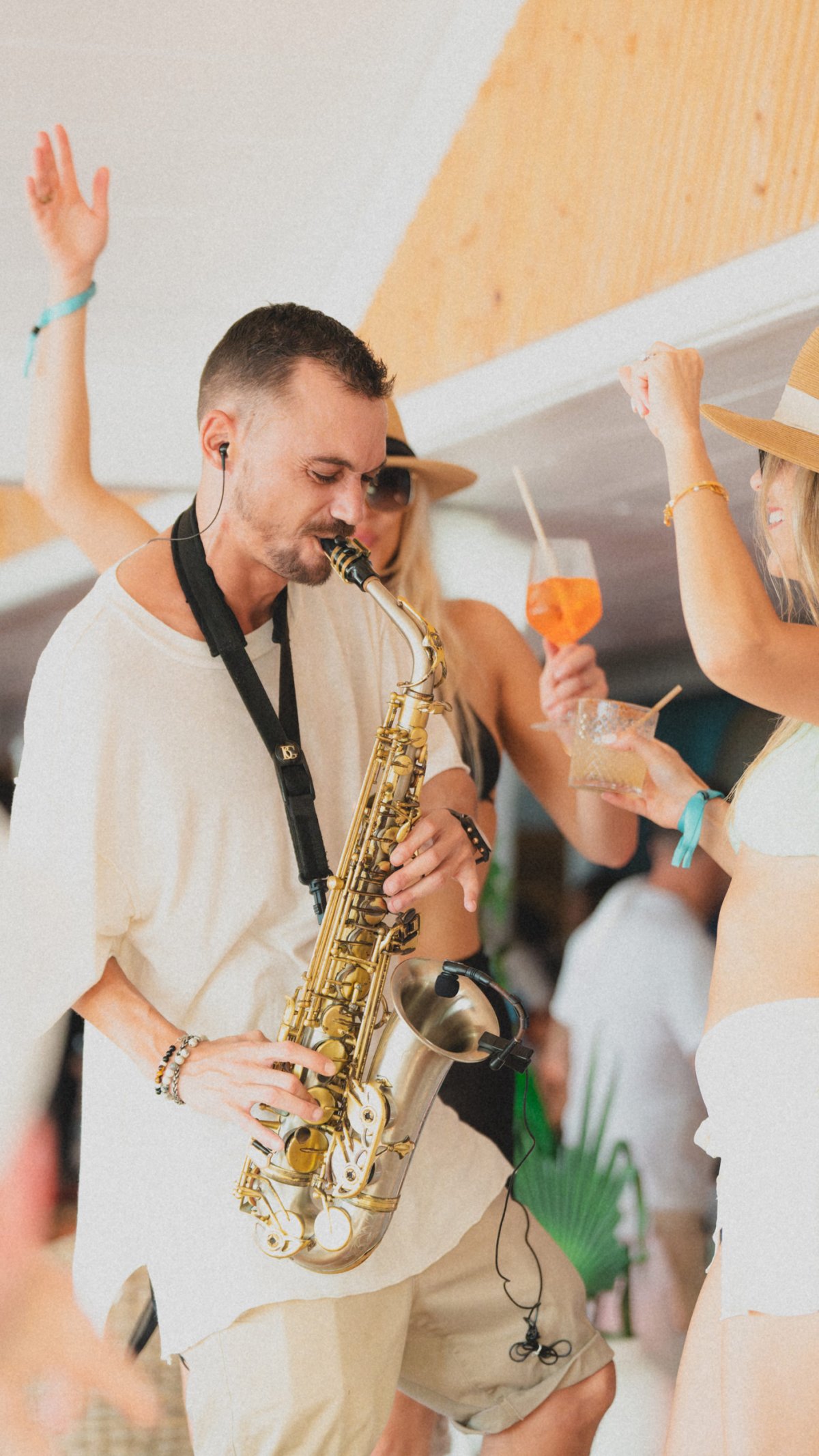 Man in a white shirt playing the saxaphone with a dancing crowd