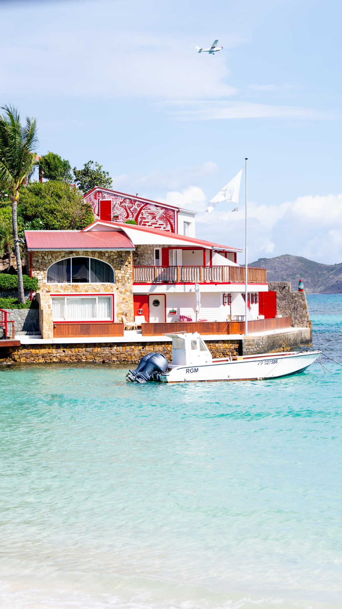 A house next to the sea with a small jet boat docked beside