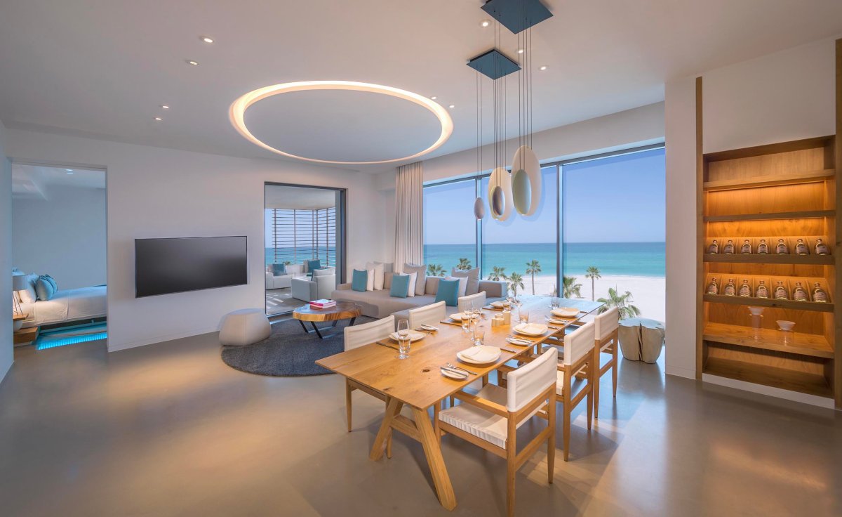 Living and dining area of Luux suite showing large sofa, dining table area and wine shelving