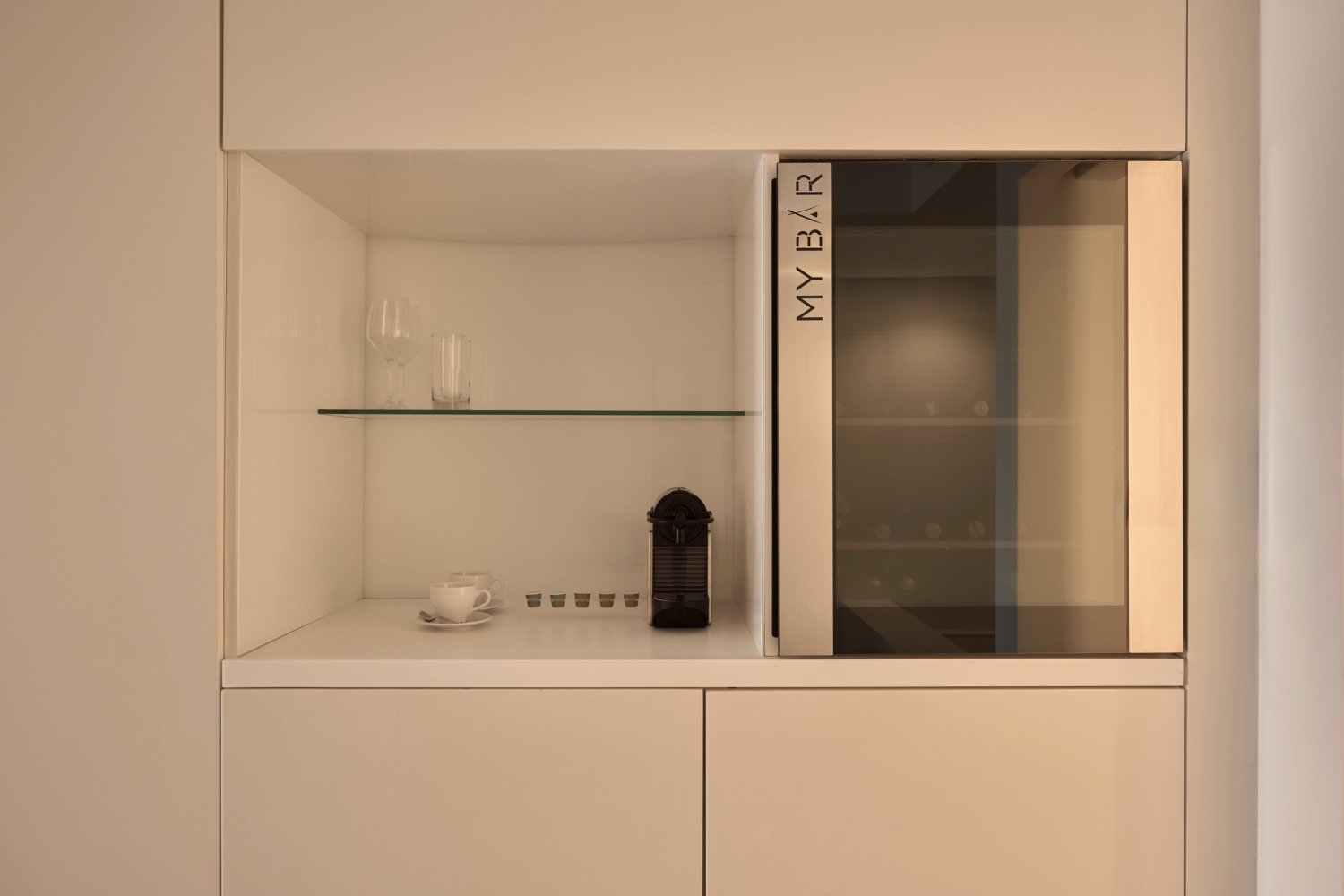 Elegant white kitchen with a glass door fridge and a modern coffee maker, ideal for enjoying serene moments at Nikki Beach