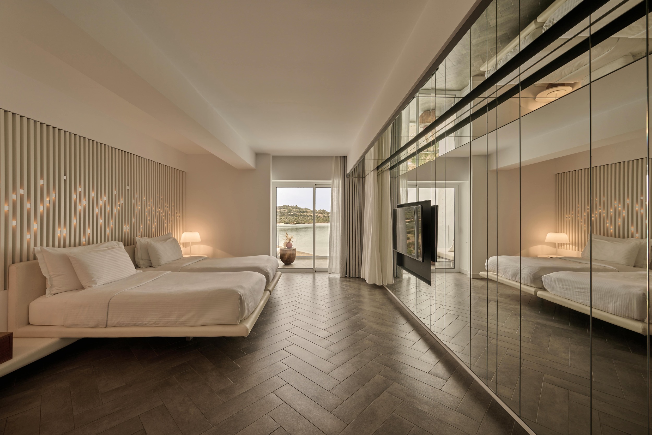 Elegant bedroom featuring two beds and a television, designed for relaxation and intimacy at Nikki Beach Porto Heli