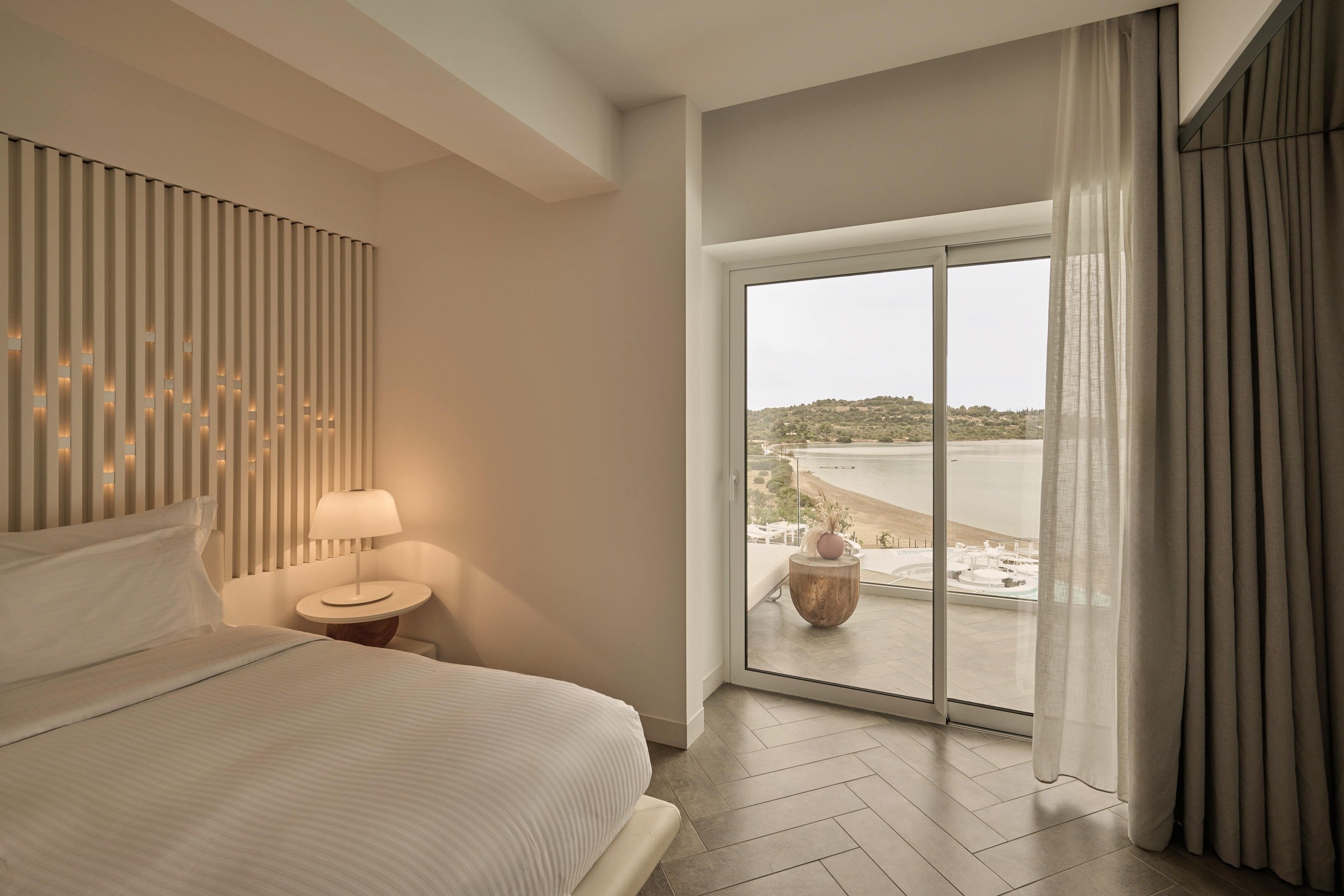 Elegant bedroom featuring a private balcony with breathtaking beach and ocean views, ideal for a serene escape