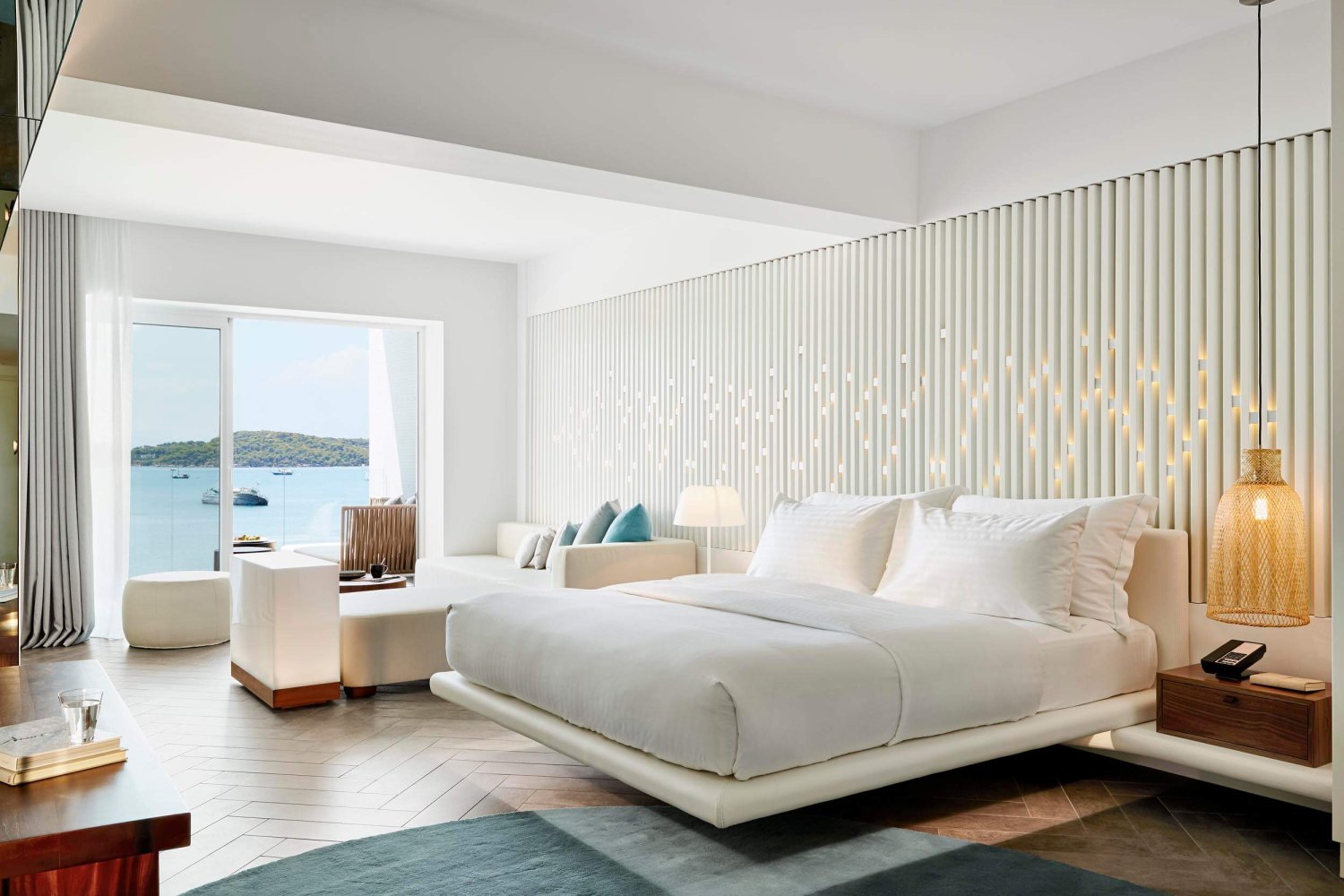 Double bed with sofa area and balcony looking out to the sea