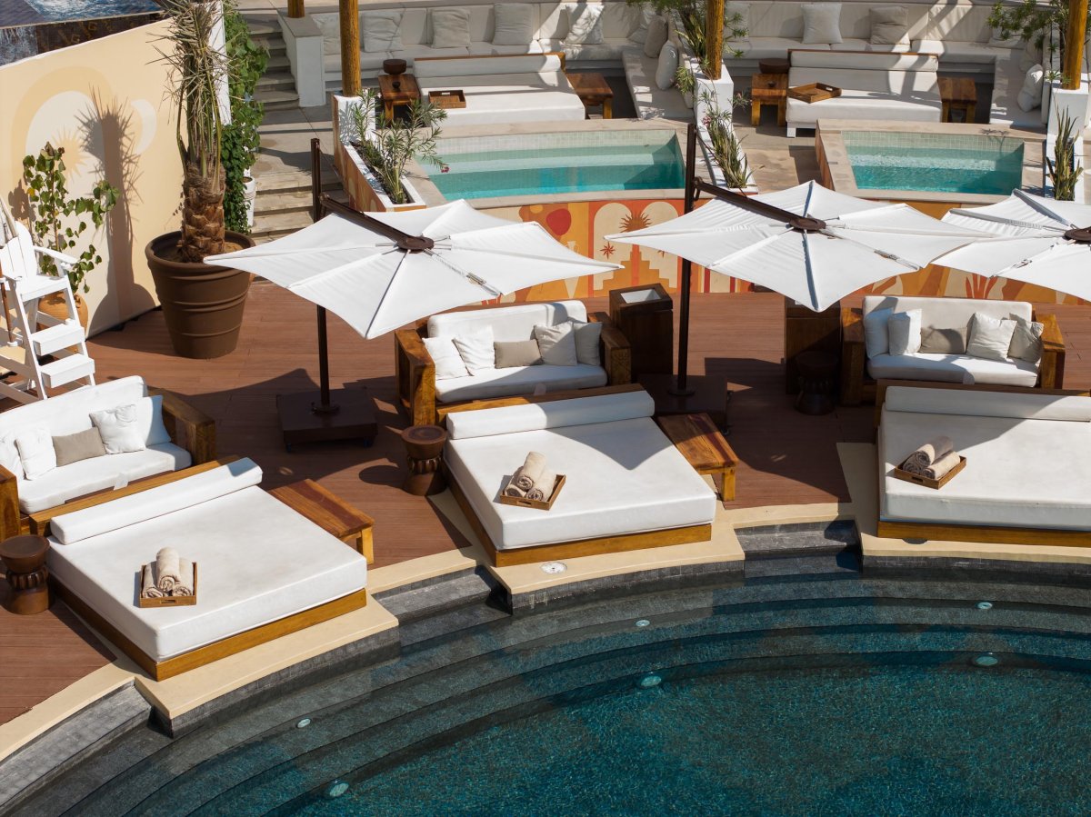 Sun beds and sofas surrounding the edge of a pool