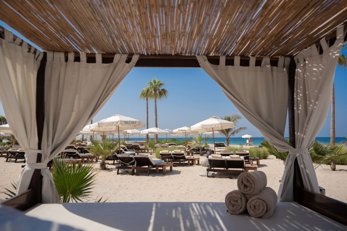 A sun bed with curtains on the beach looking out to the sea