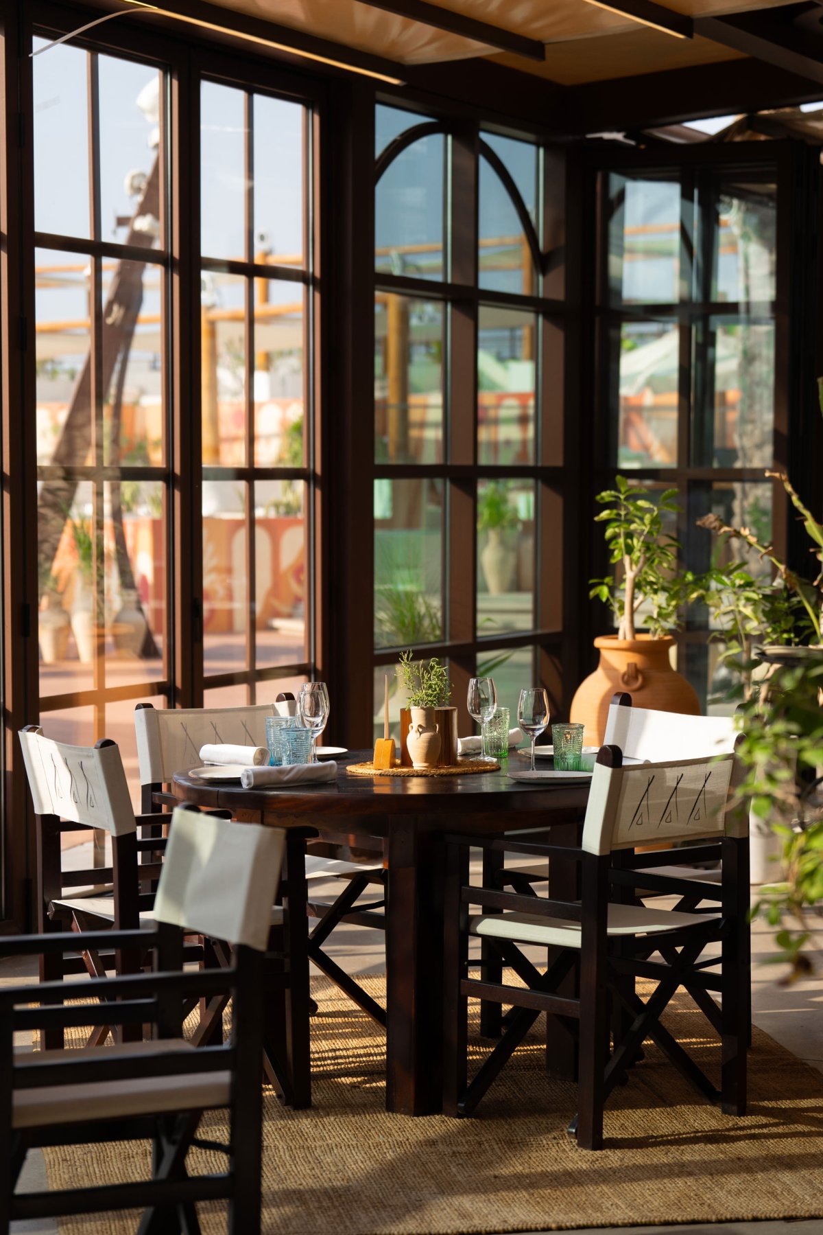 Nikki Beach restaurant dining table and chairs with floor to ceiling windows looking out to the pool area