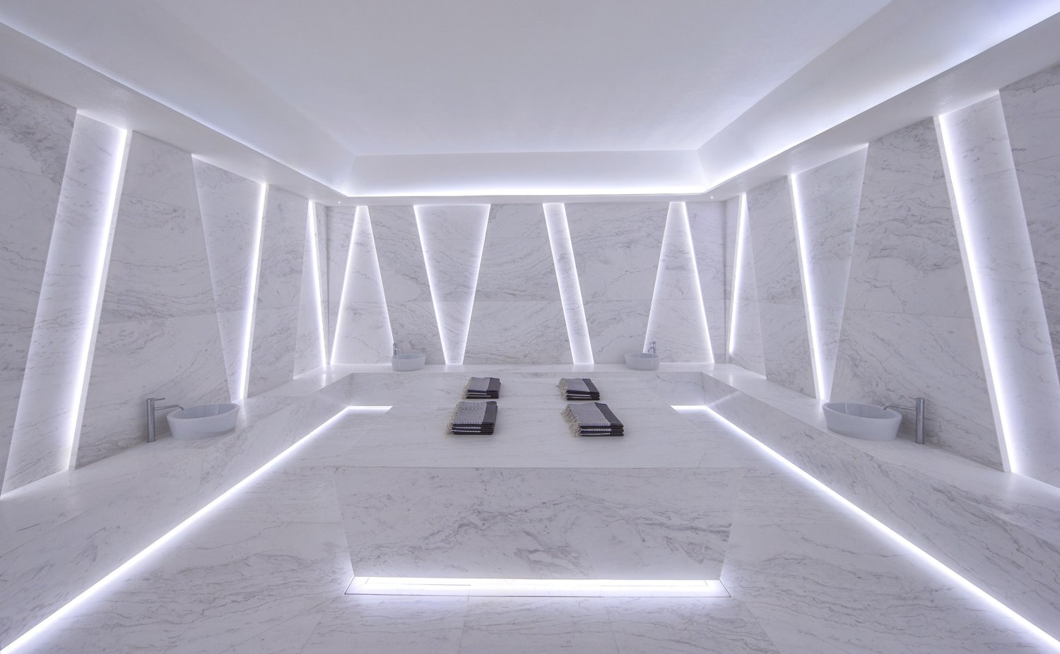 Elegant marble room featuring soft white lighting and a sleek sink, embodying luxury and tranquility