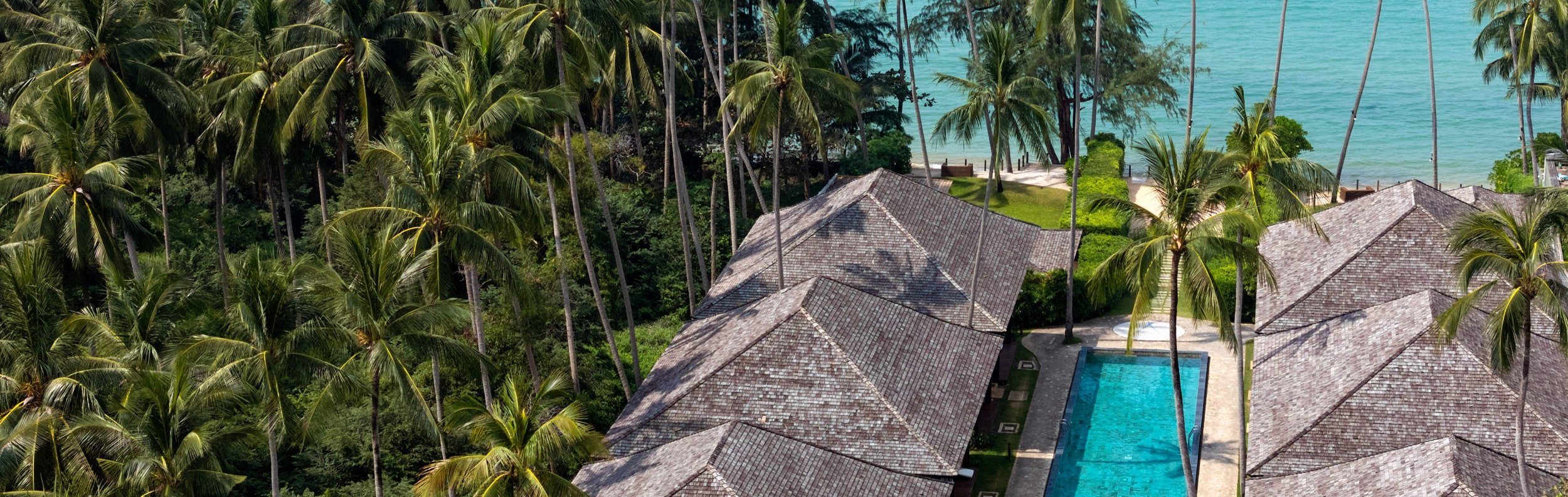 Aerial view of Nikki Beach Resort & Spa, surrounded by palm trees and overlooking the serene Lipa Noi Beach and its soft sands