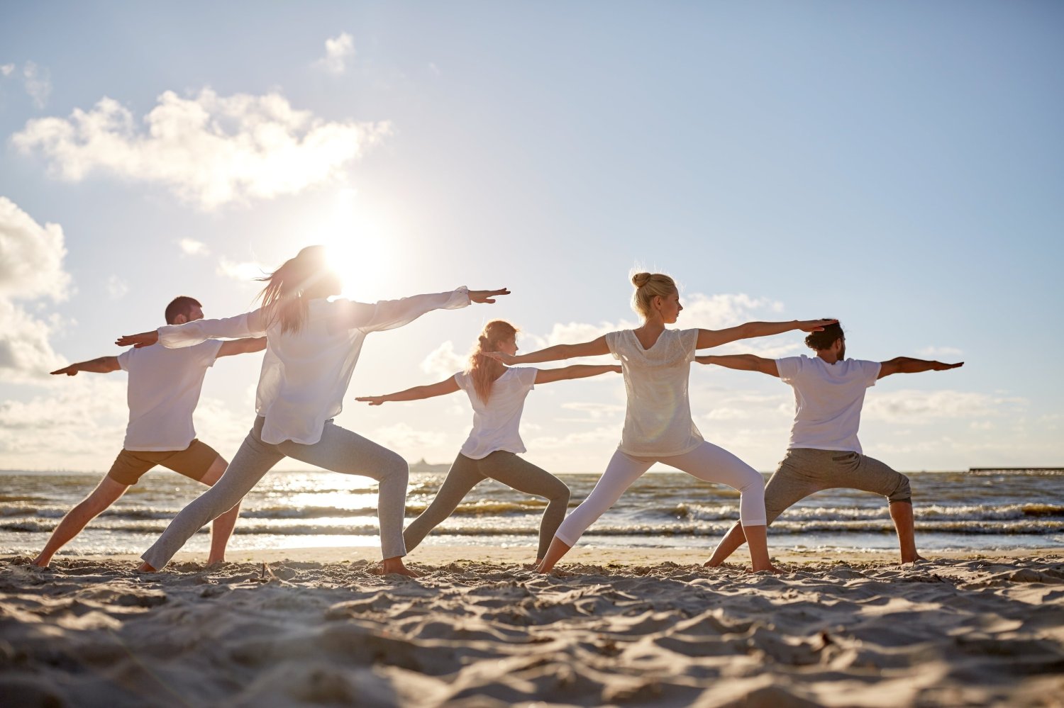 A serene beach scene with a group practicing yoga, guided by Nicki Petroulaki, embodying tranquility and rejuvenation