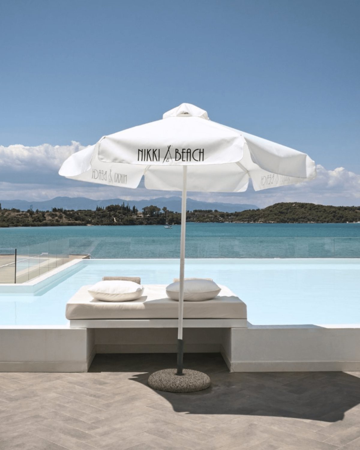 A sun-drenched lounger beneath crisp white umbrellas, where sea and sky merge into pure tranquility