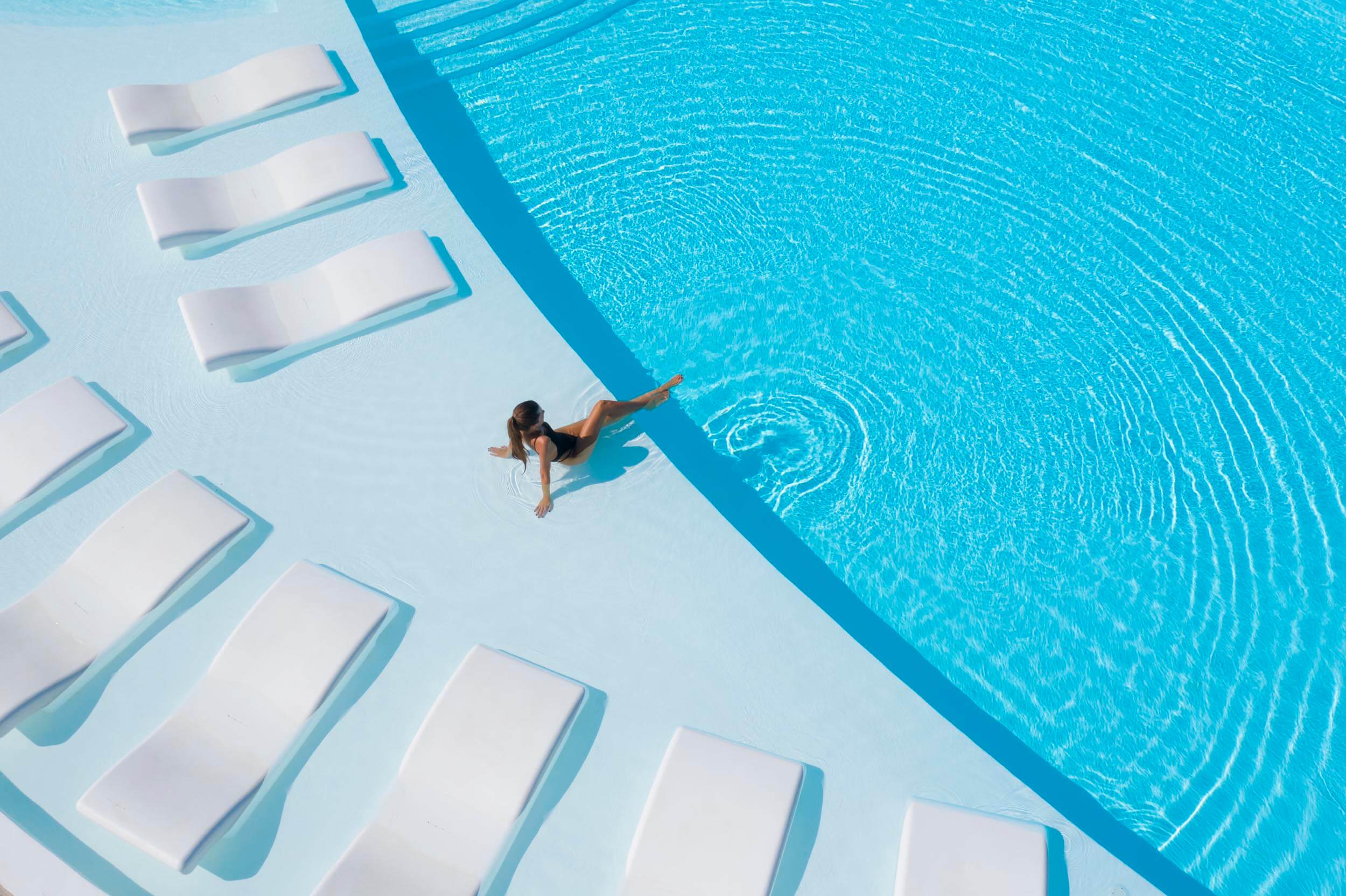 A women lounging on the edge of the pool, with her legs in the water